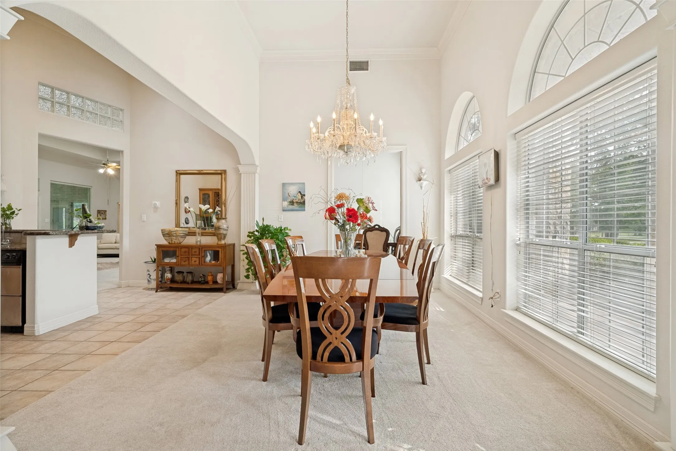 Foyer with high ceilings featuring a large chandelier,  prominent fluted column, arched doorways, tile flooring with decorative inlay, and a double entry door with leaded glass sidelights and windows