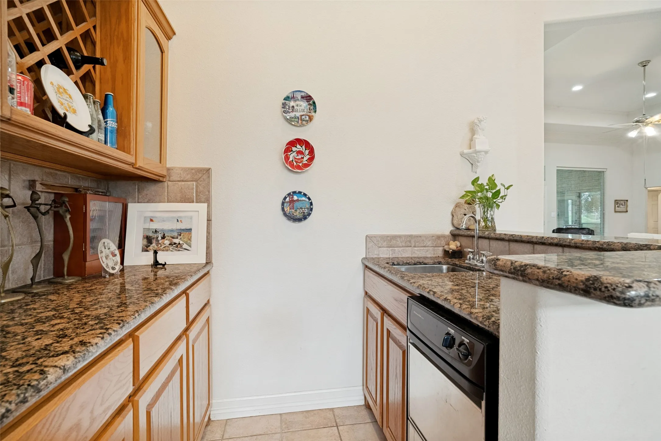 Wet bar area featuring granite countertops, wood cabinetry, a built-in wine rack, tile backsplash, and an undermount sink