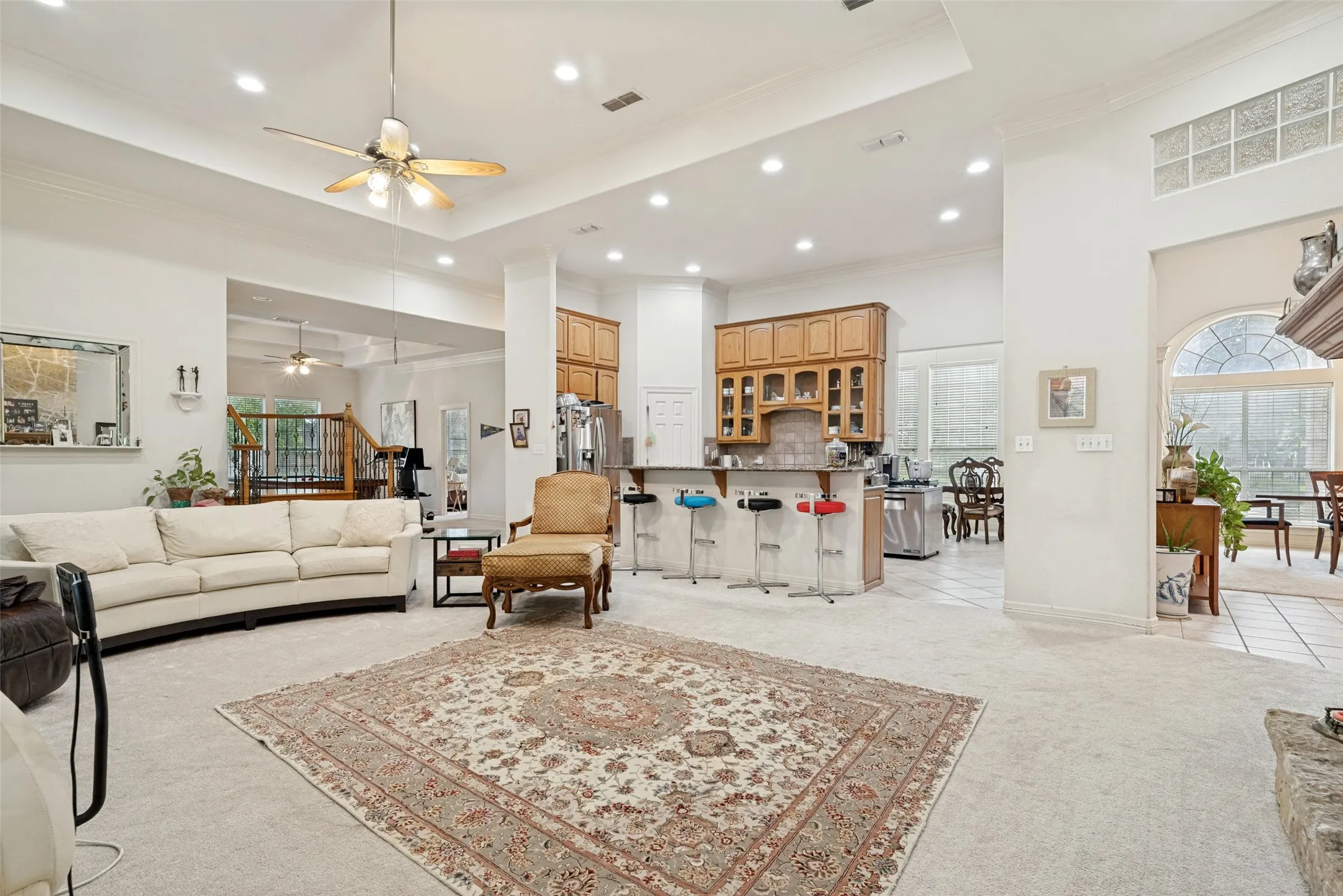Expansive open-concept living area featuring high ceilings, recessed lighting, and carpet flooring