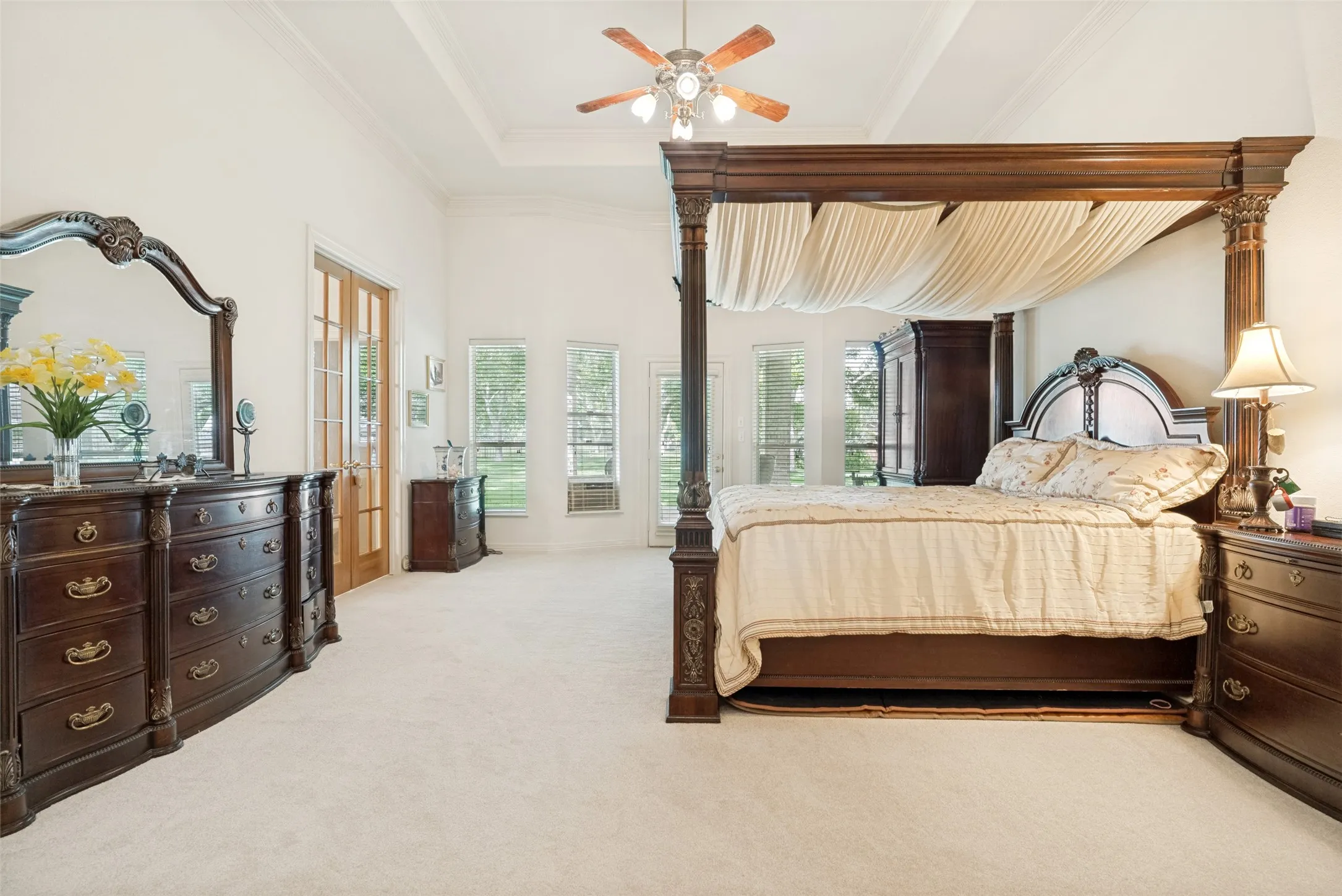 Spacious room featuring a mutli-tray ceiling, ceiling fan, light-toned carpet flooring, door to exterior