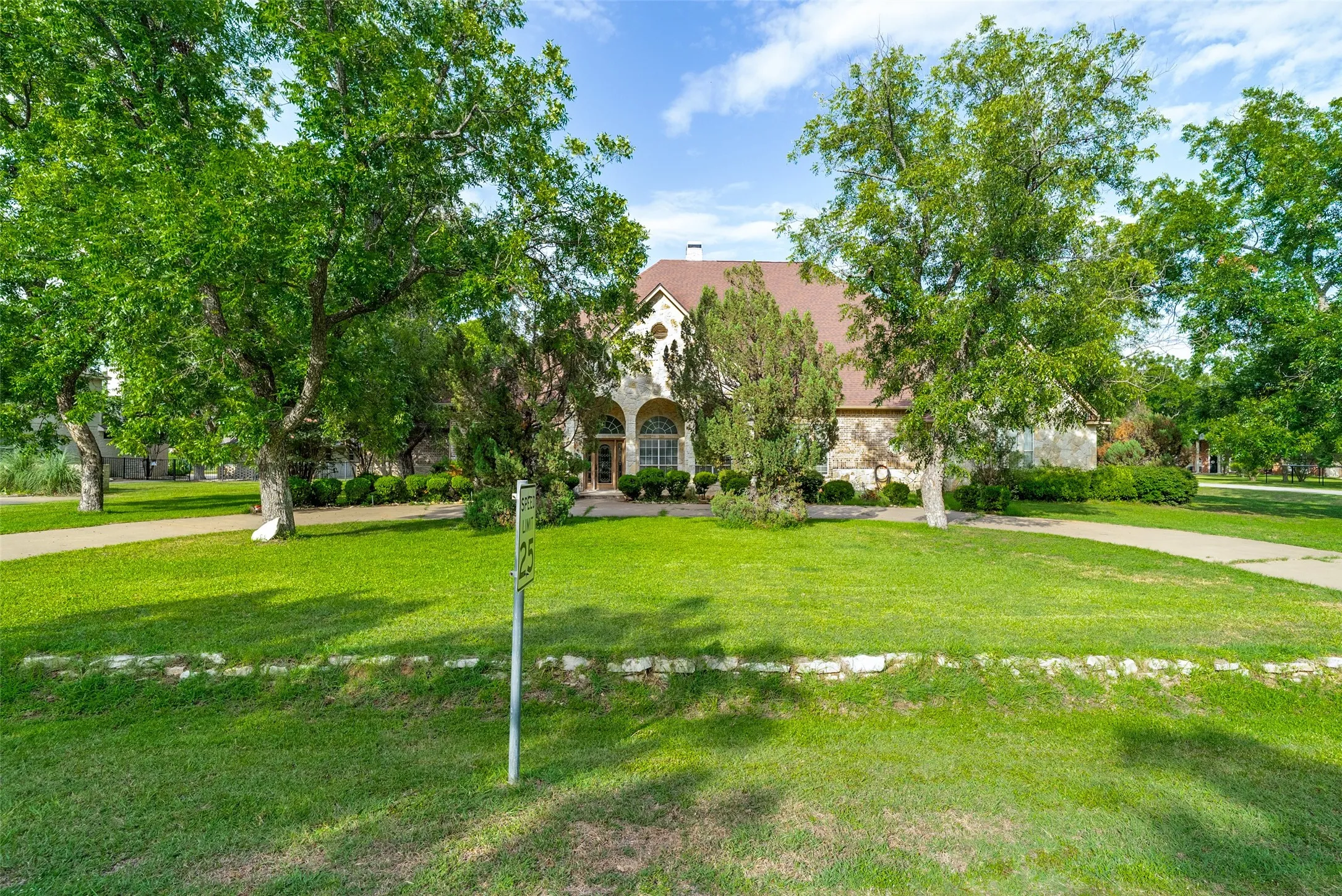 Stone facade residence featuring arched entry, semi-circle driveway