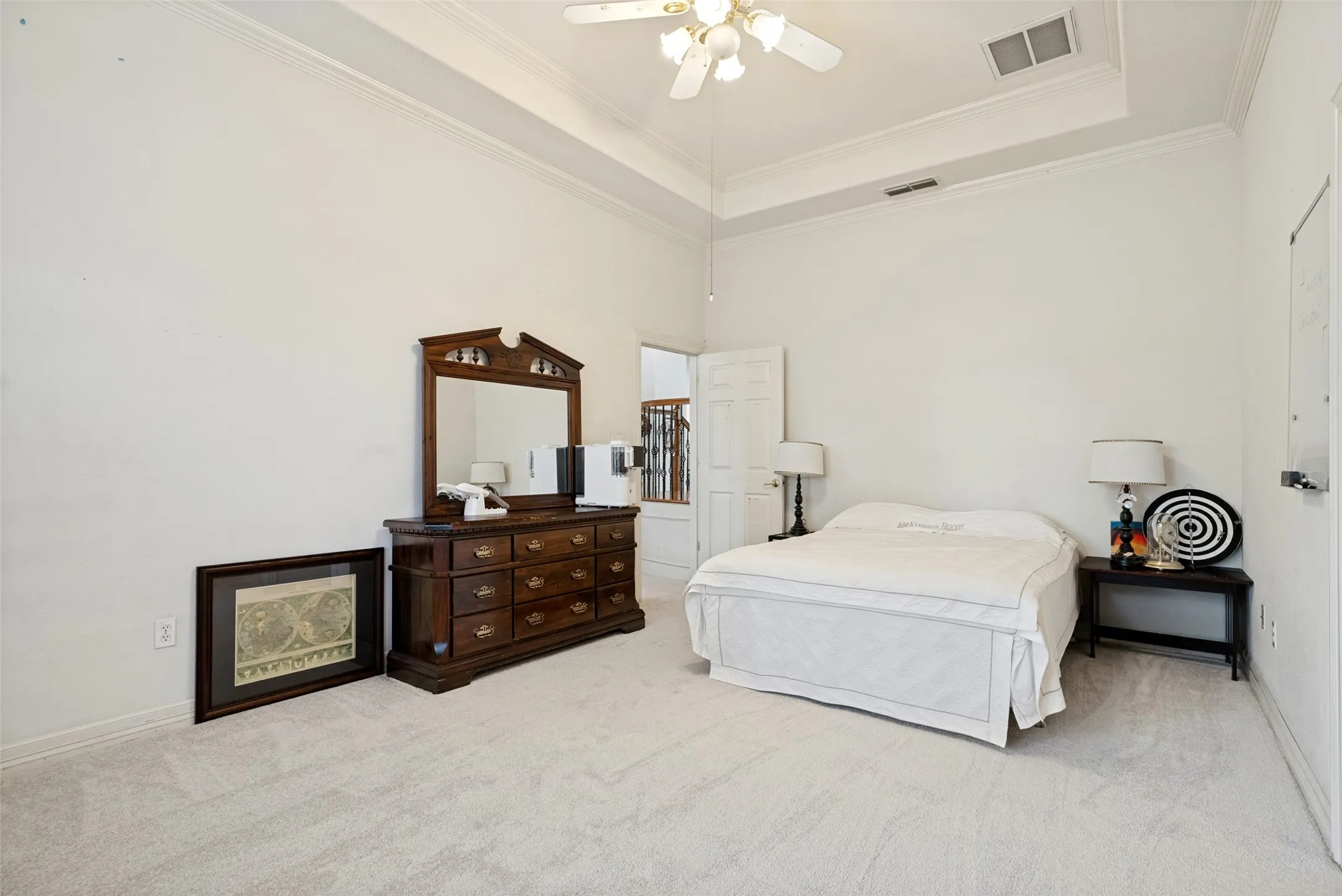 Spacious room featuring tray ceiling,  crown molding, light neutral carpet, and multiple windows, walk-in closet and onsuite bathroom