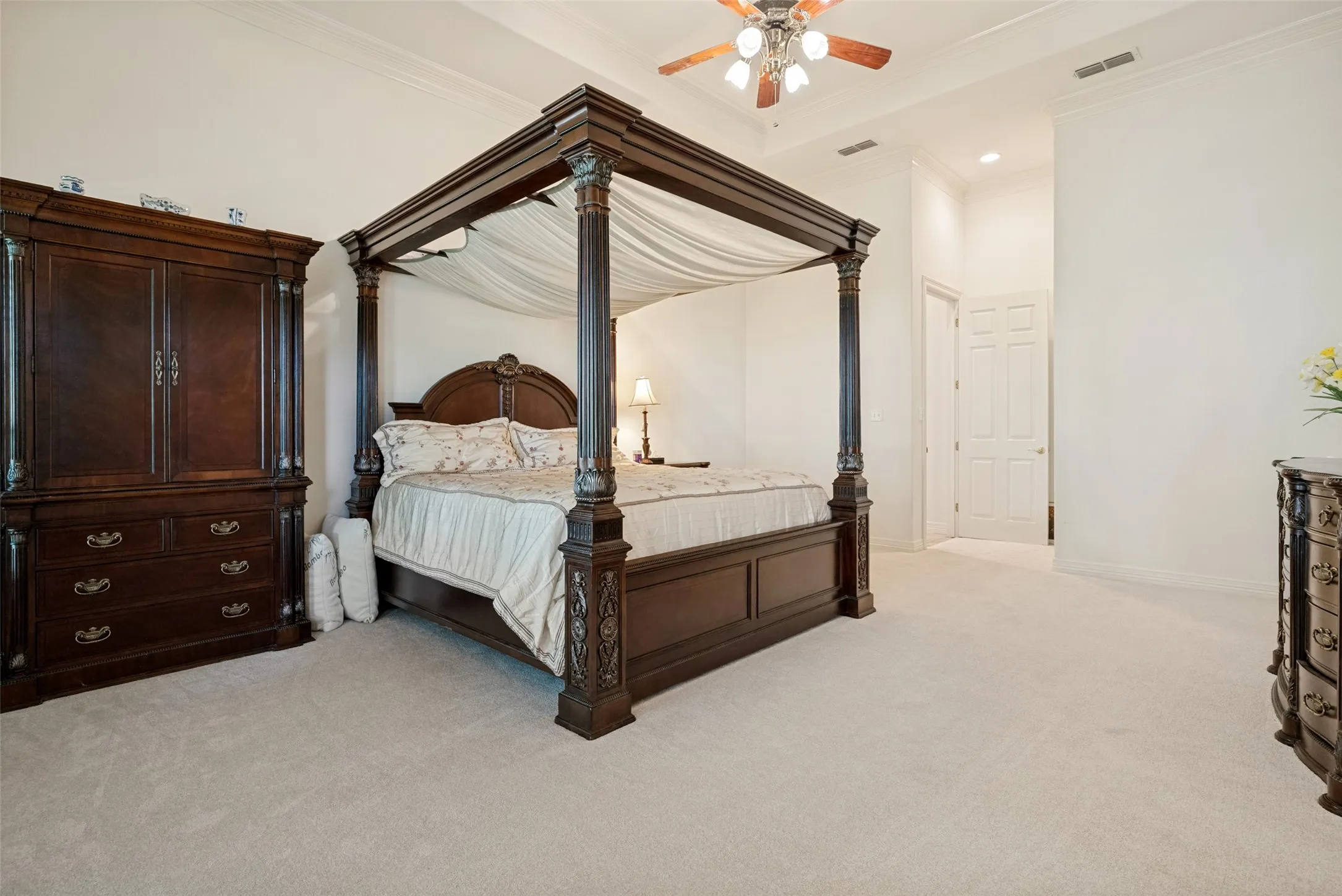 Spacious room featuring a mutli-tray ceiling, ceiling fan, light-toned carpet flooring, door to exterior