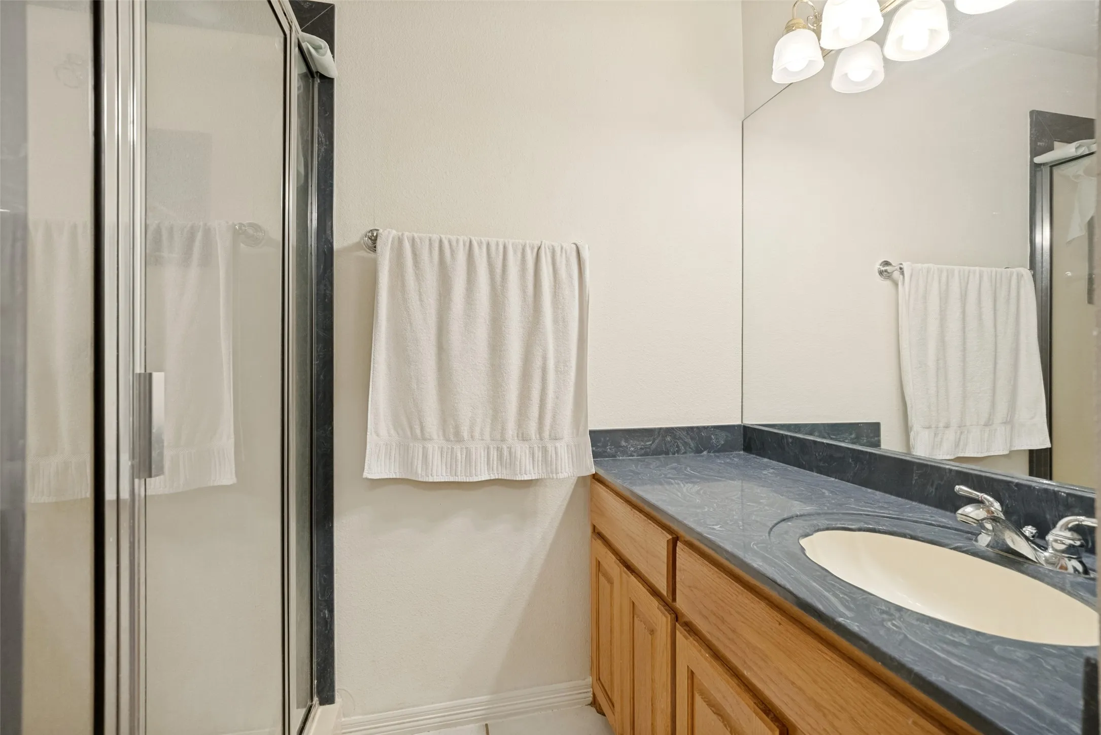 Bathroom vanity with a dark countertop, an integrated sink, and a chrome fixtures
