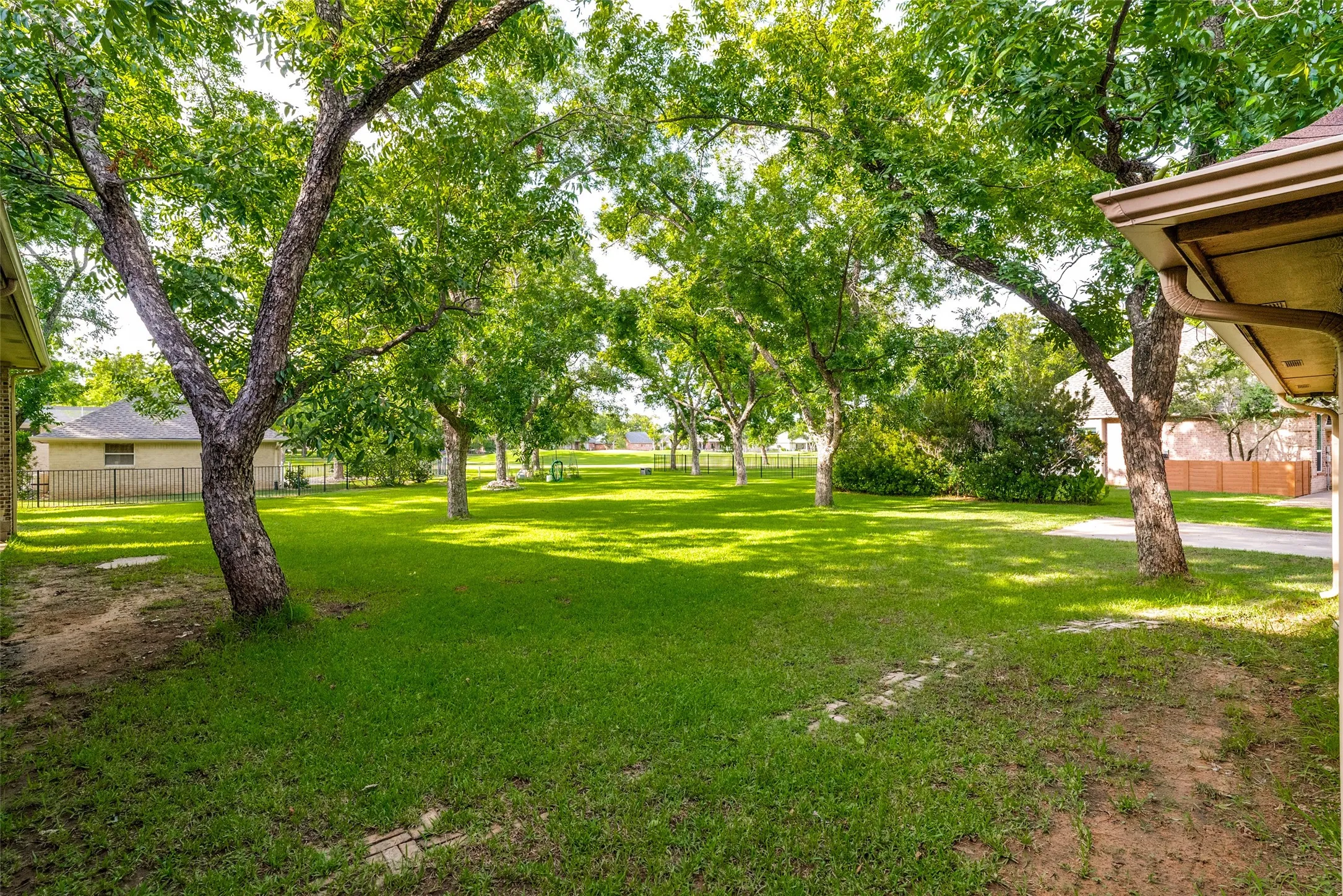 Expansive green lawn framed by mature trees, creating natural shade