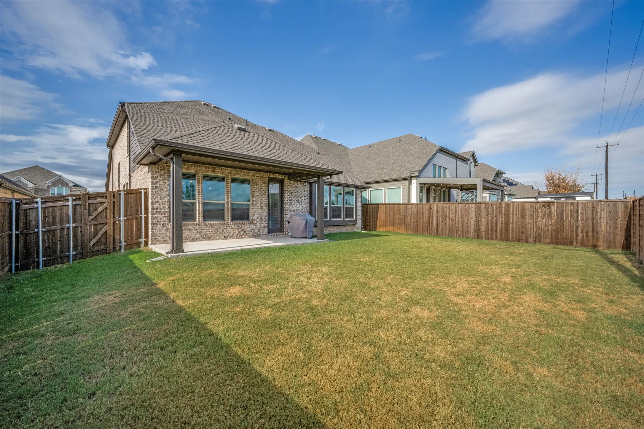 Expansive backyard featuring a covered patio with concrete flooring, a large grassy area, and a privacy fence