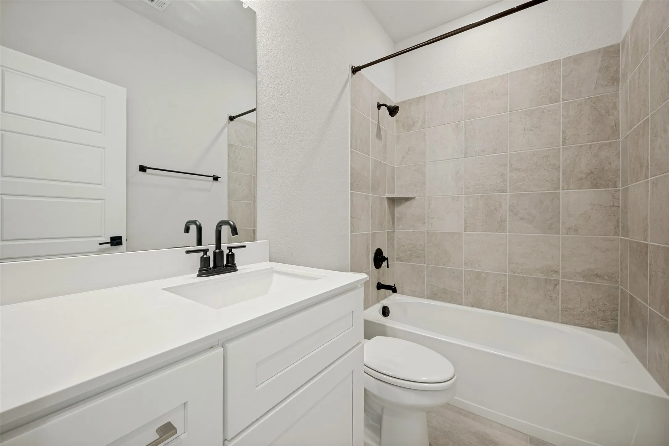 Bathroom featuring a white vanity with an integrated sink, matte black fixtures, a white soaking tub, and subway tile surround with a built-in niche