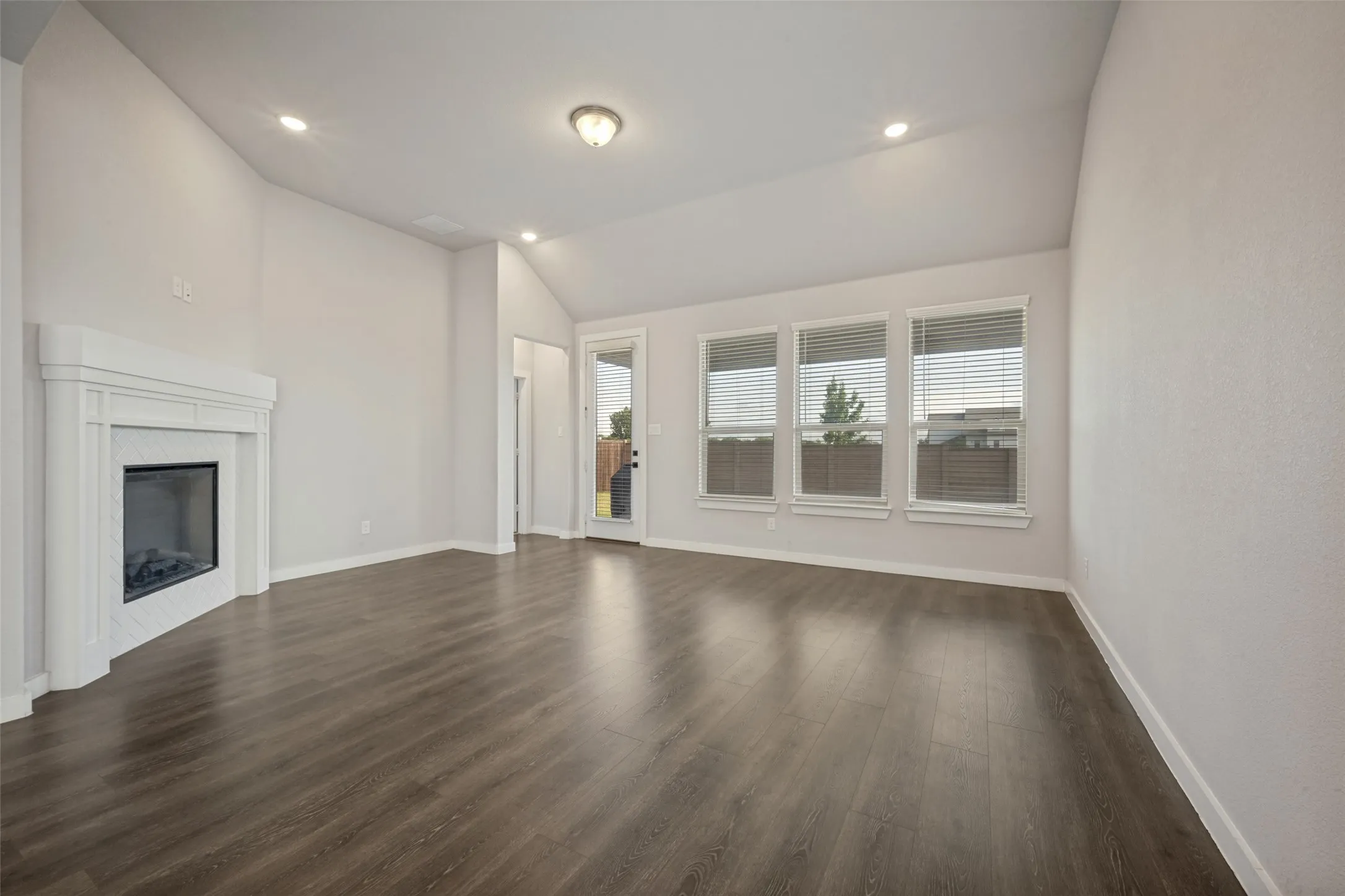 Spacious living area featuring a vaulted ceiling and wood-finish flooring