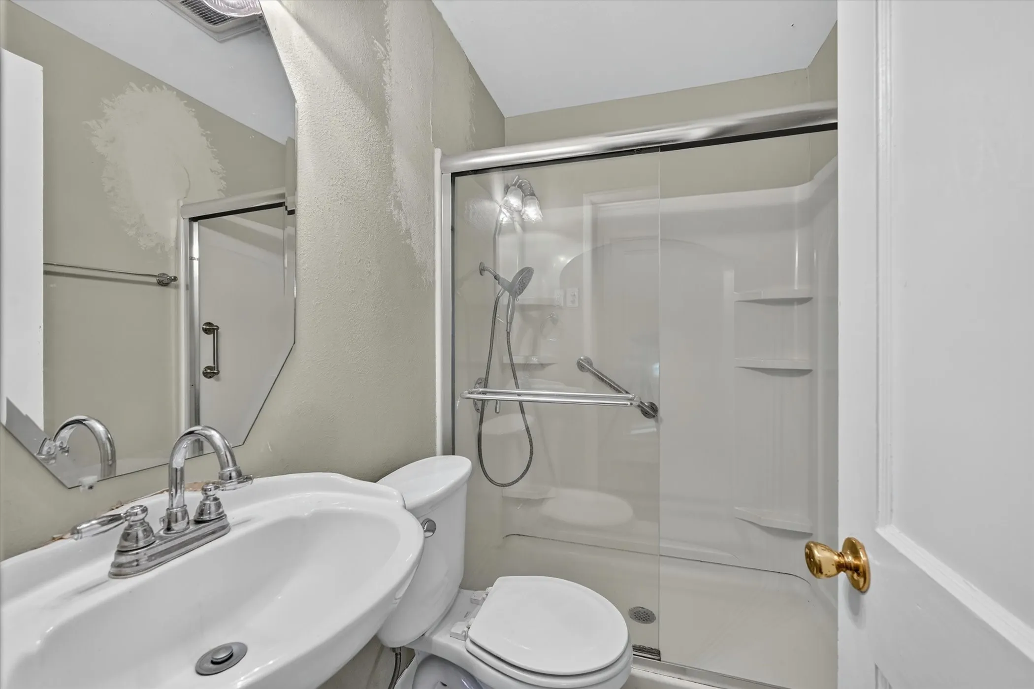 Full bathroom featuring a walk-in shower with clear glass enclosure and built-in shelving, a white ceramic toilet, and a white pedestal sink with chrome fixtures
