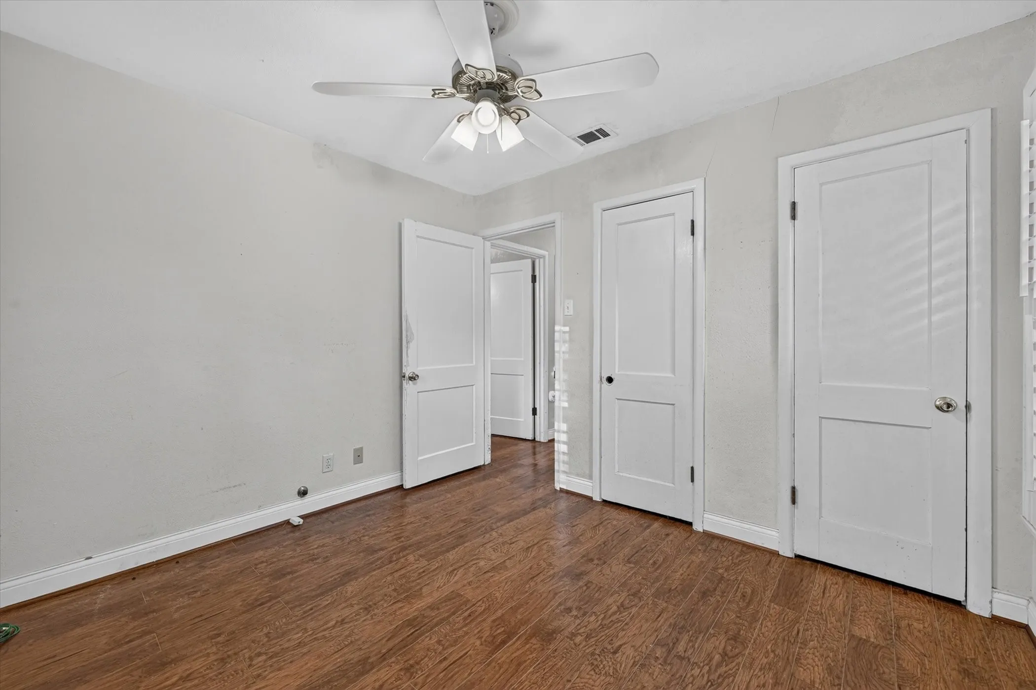 Room featuring wood-finish flooring, white baseboards, and light gray walls