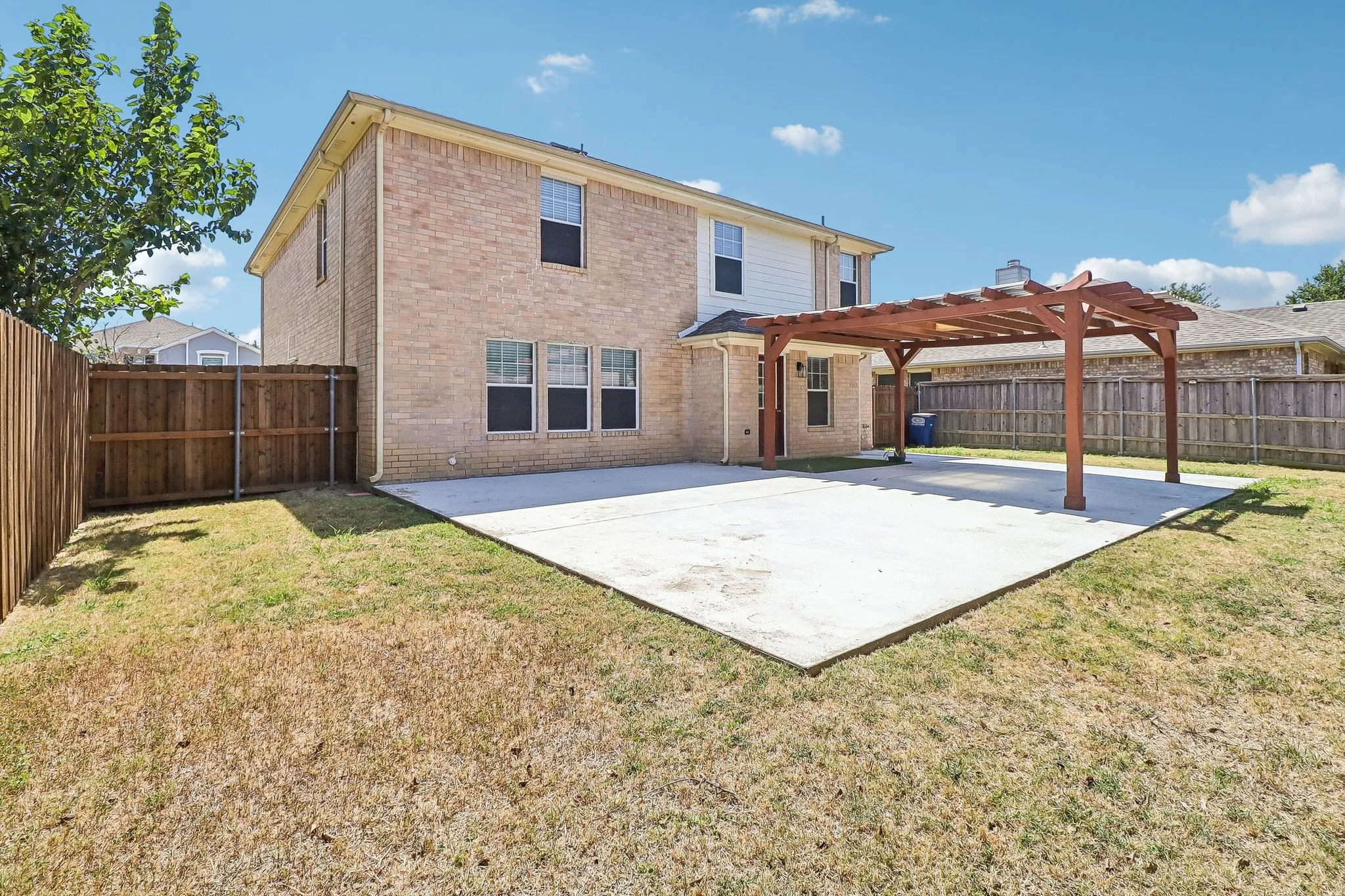 Expansive concrete patio with an attached wood pergola