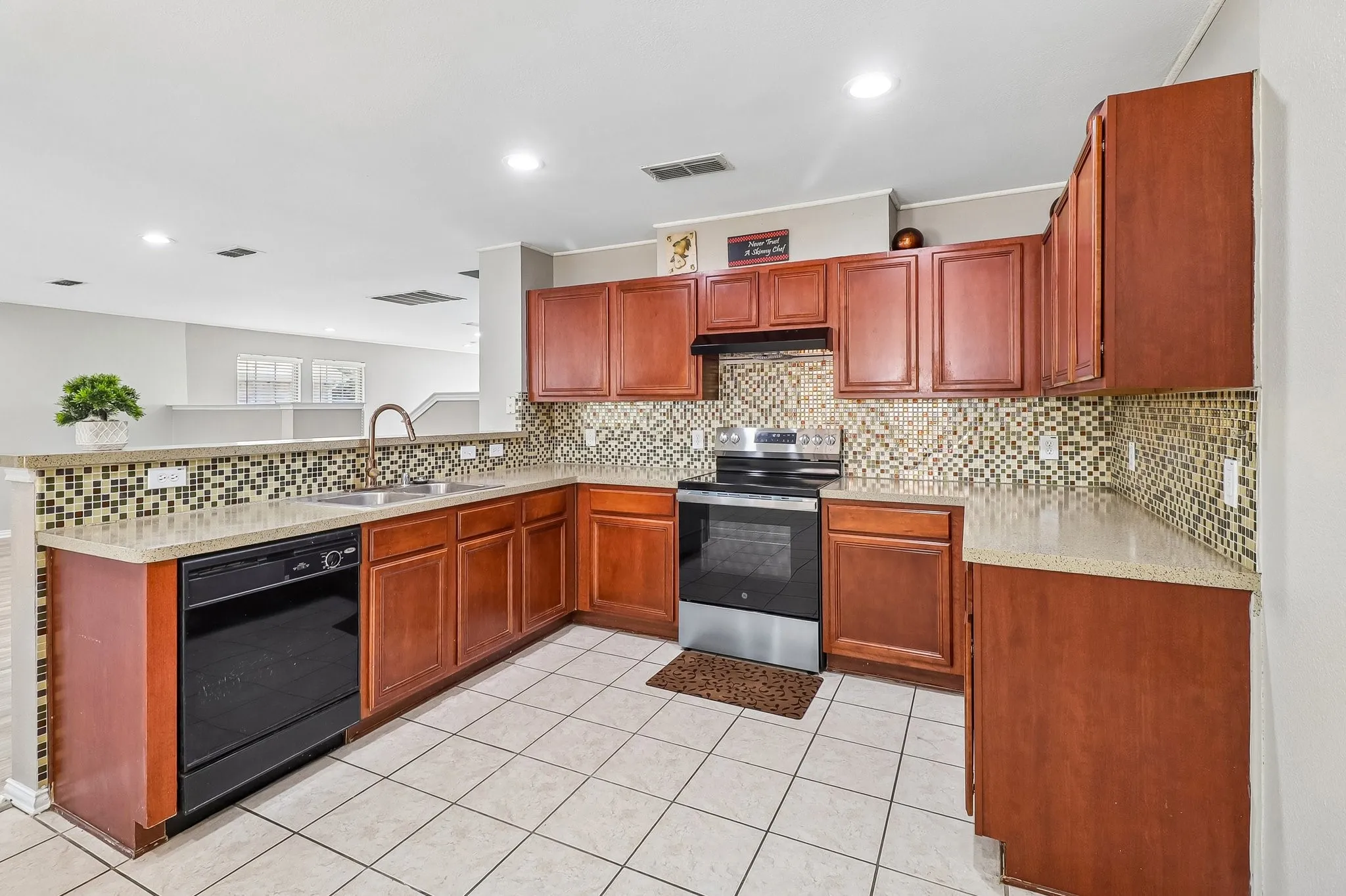 Kitchen featuring rich wood cabinetry, patterned tile backsplash, and light-toned countertops