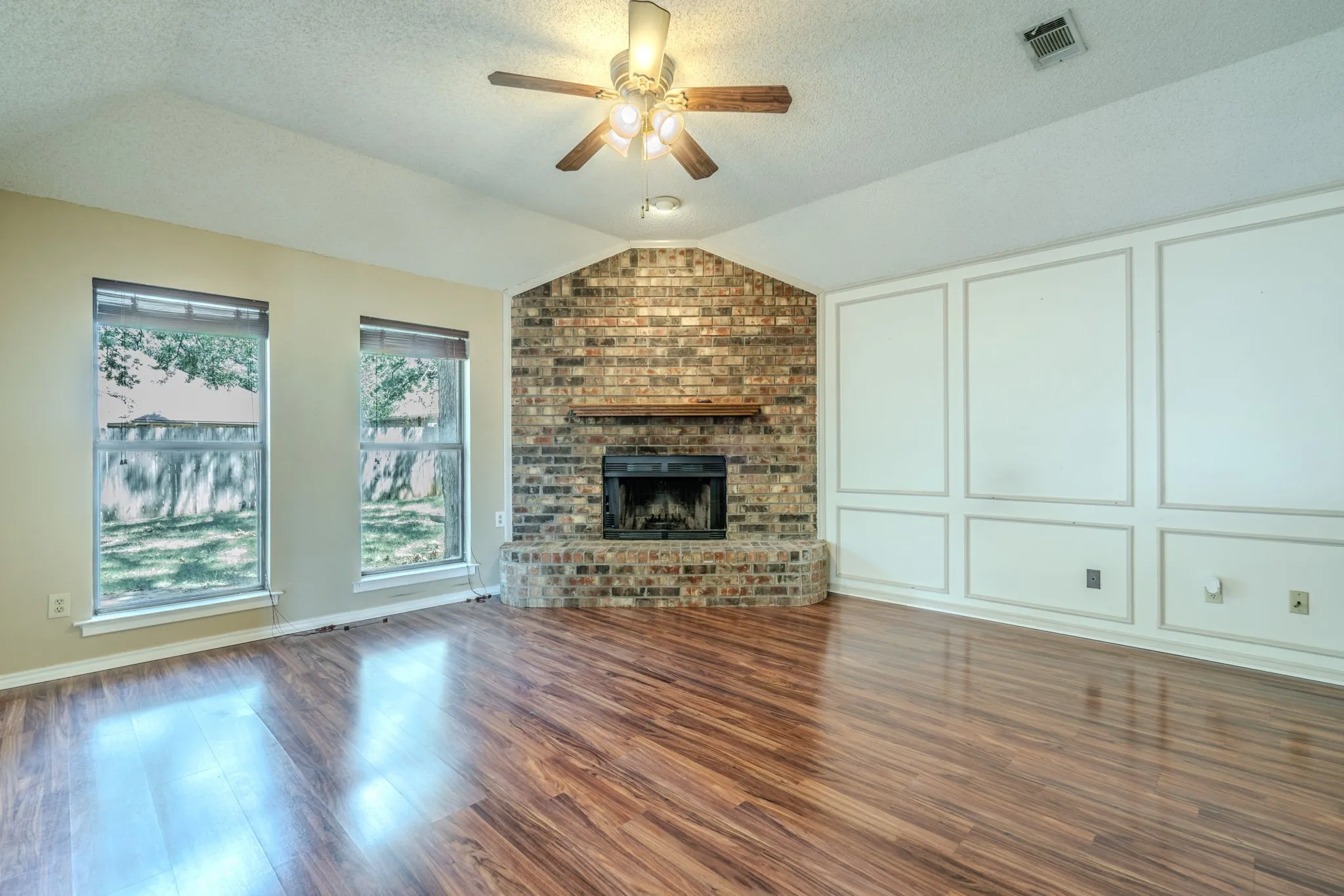 Spacious living area features a floor to ceiling brick fireplace.
