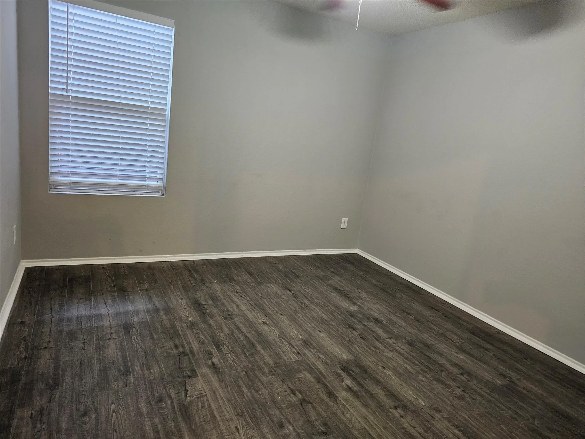 Unfurnished room featuring dark wood finished floors and ceiling fan