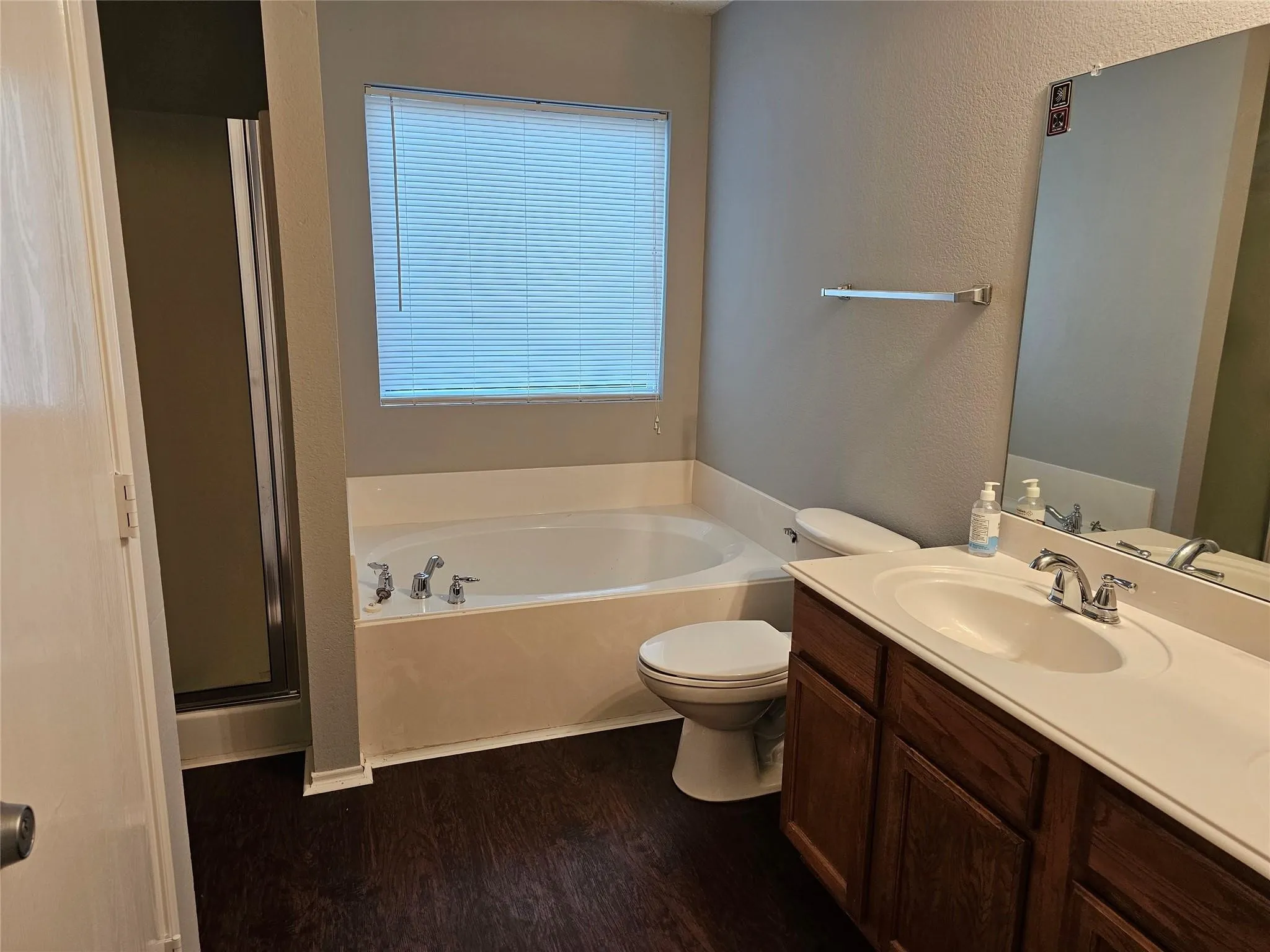 Bathroom featuring a garden tub, vanity, a textured wall, dark wood finished floors, and a shower stall