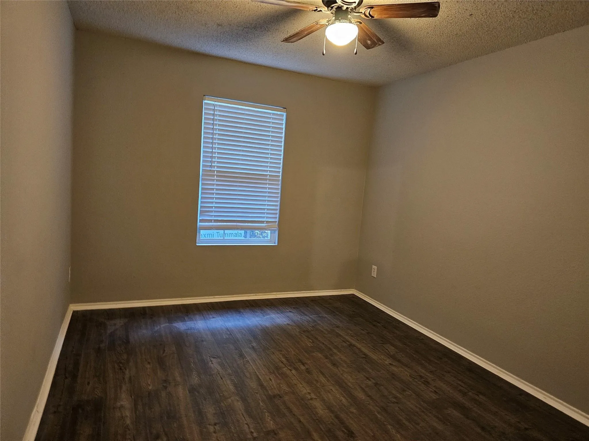 Unfurnished room with dark wood-type flooring, a textured ceiling, and a ceiling fan