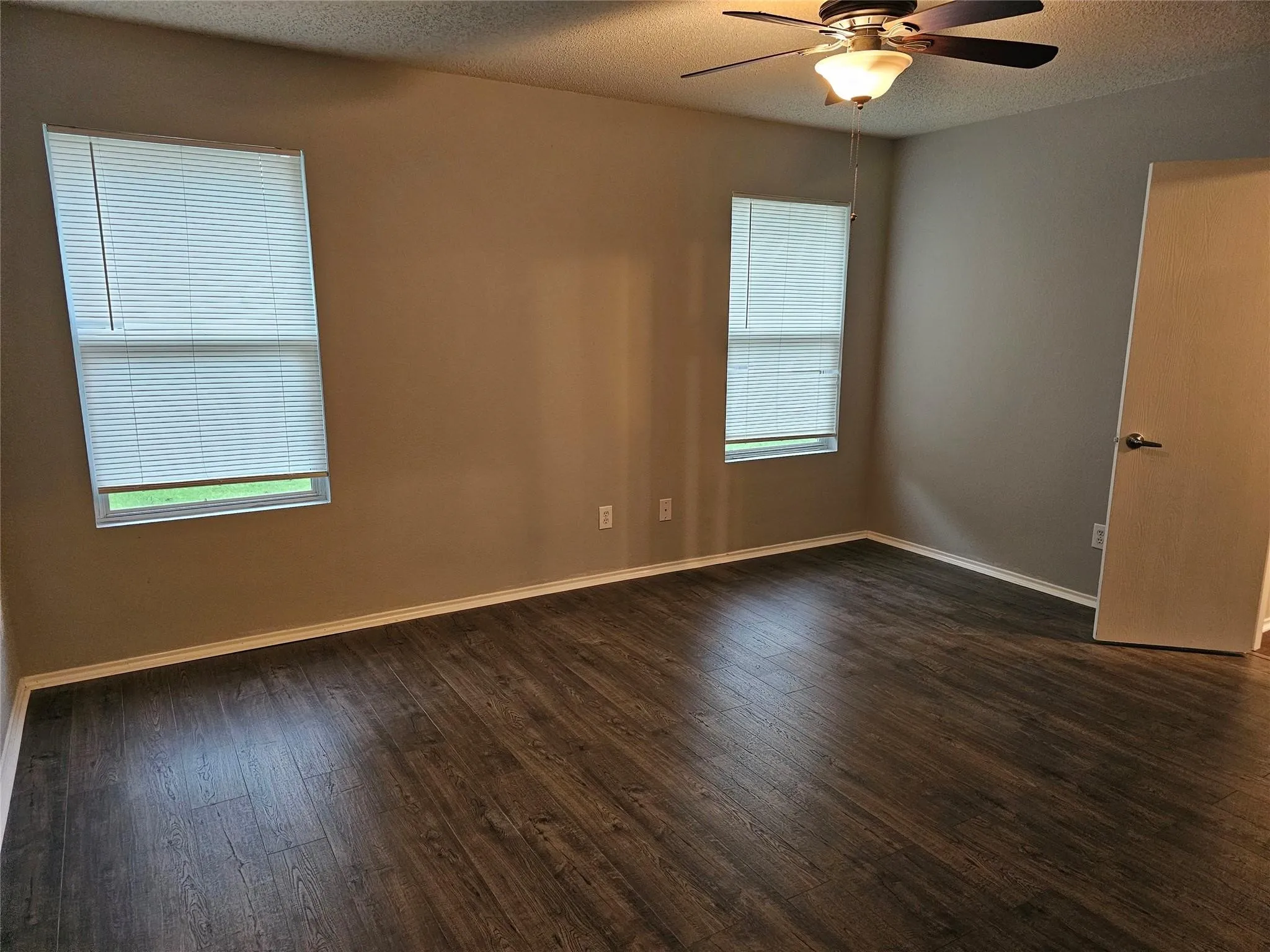Unfurnished room with a textured ceiling, dark wood finished floors, and a ceiling fan