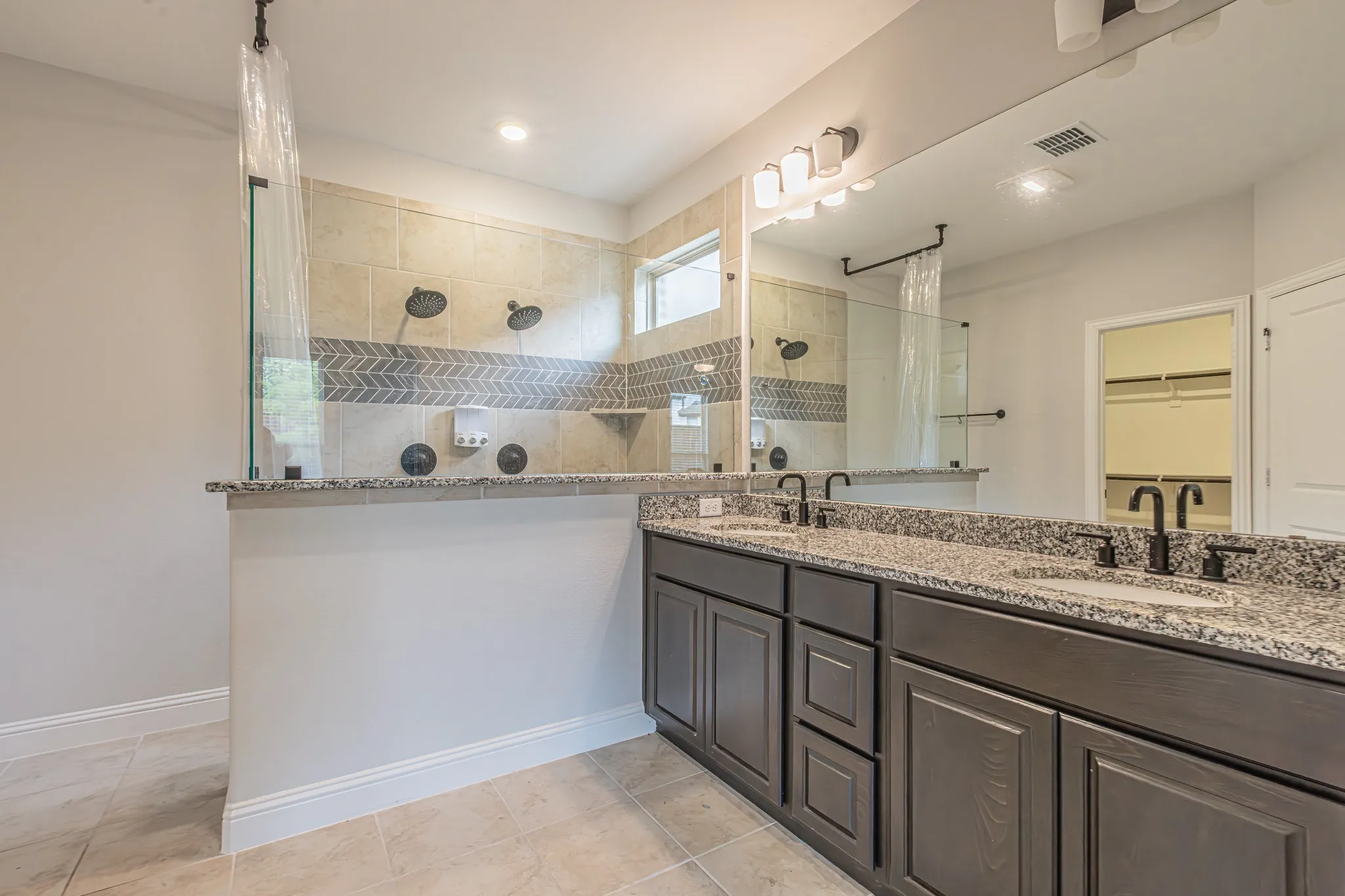 Spacious bathroom featuring a double vanity with granite countertops, dual sinks, and dark wood cabinetry