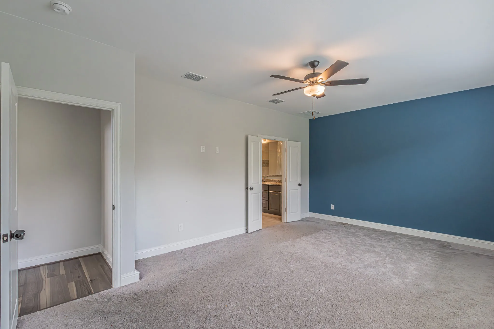 Room featuring light gray carpet flooring and a deep blue accent wall