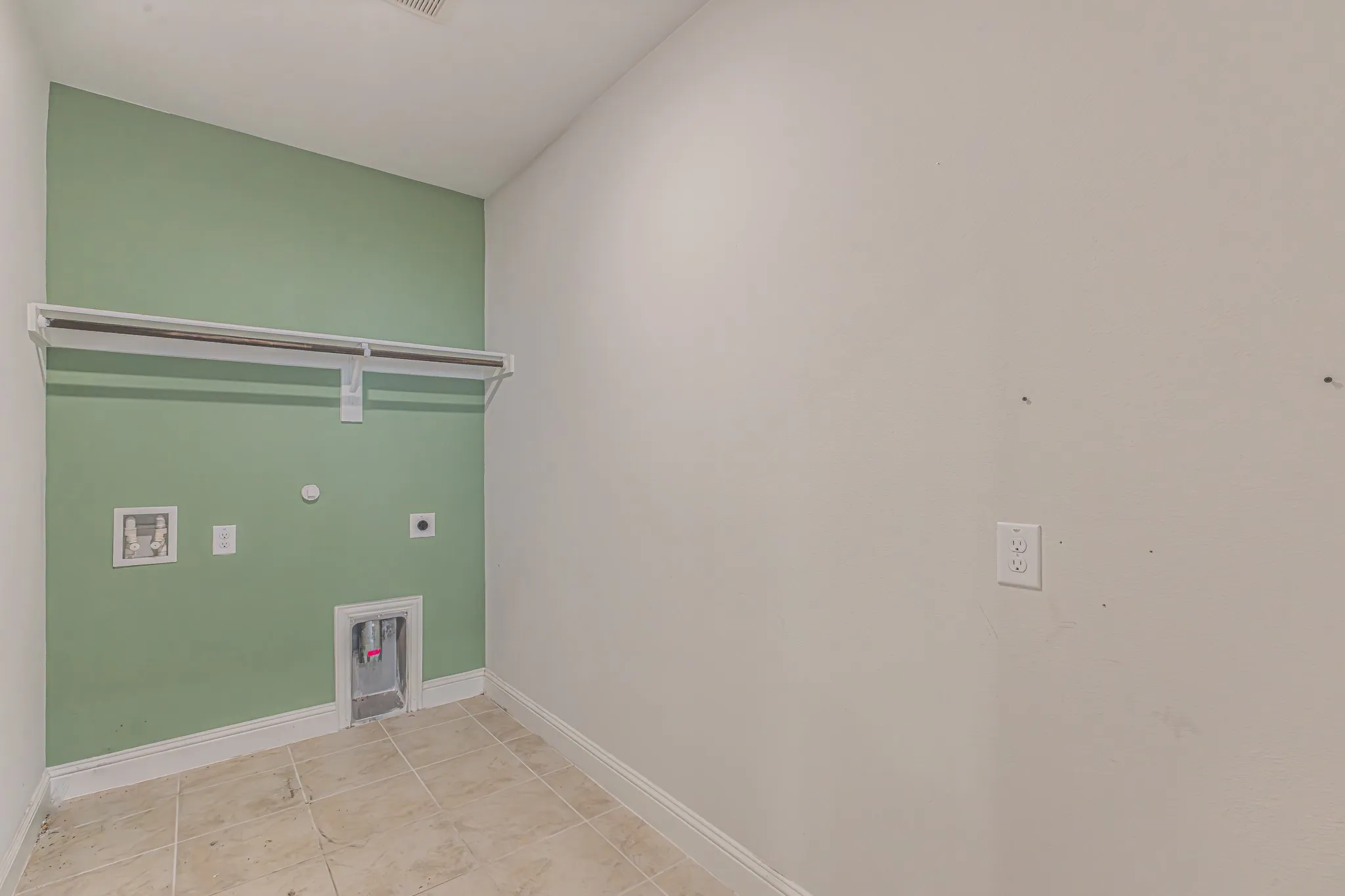Laundry area featuring tiled flooring, a built-in hanging rod, and utility hookups