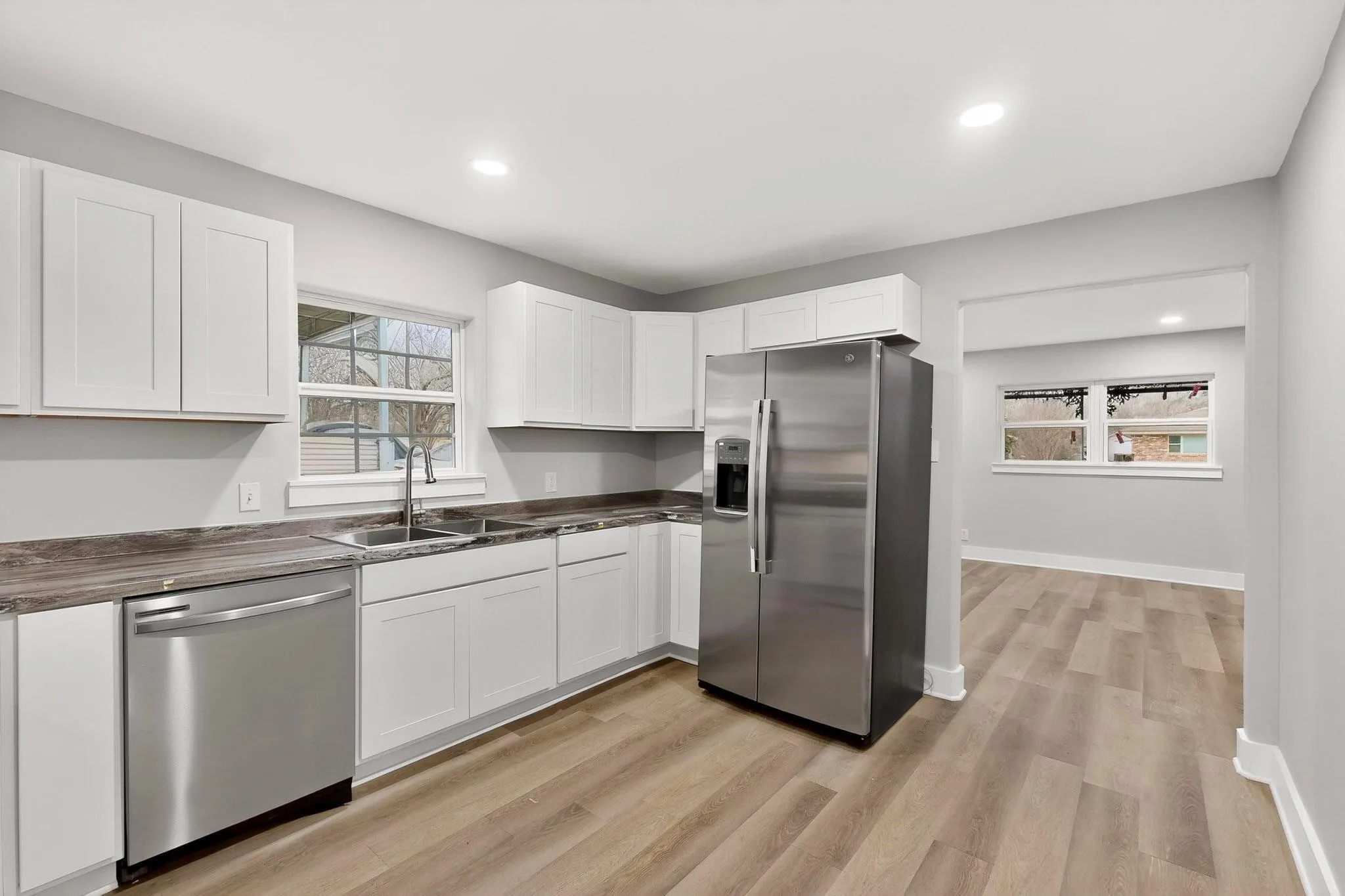 Bright kitchen featuring white shaker-style cabinetry, wood-finish countertops, and stainless steel appliances