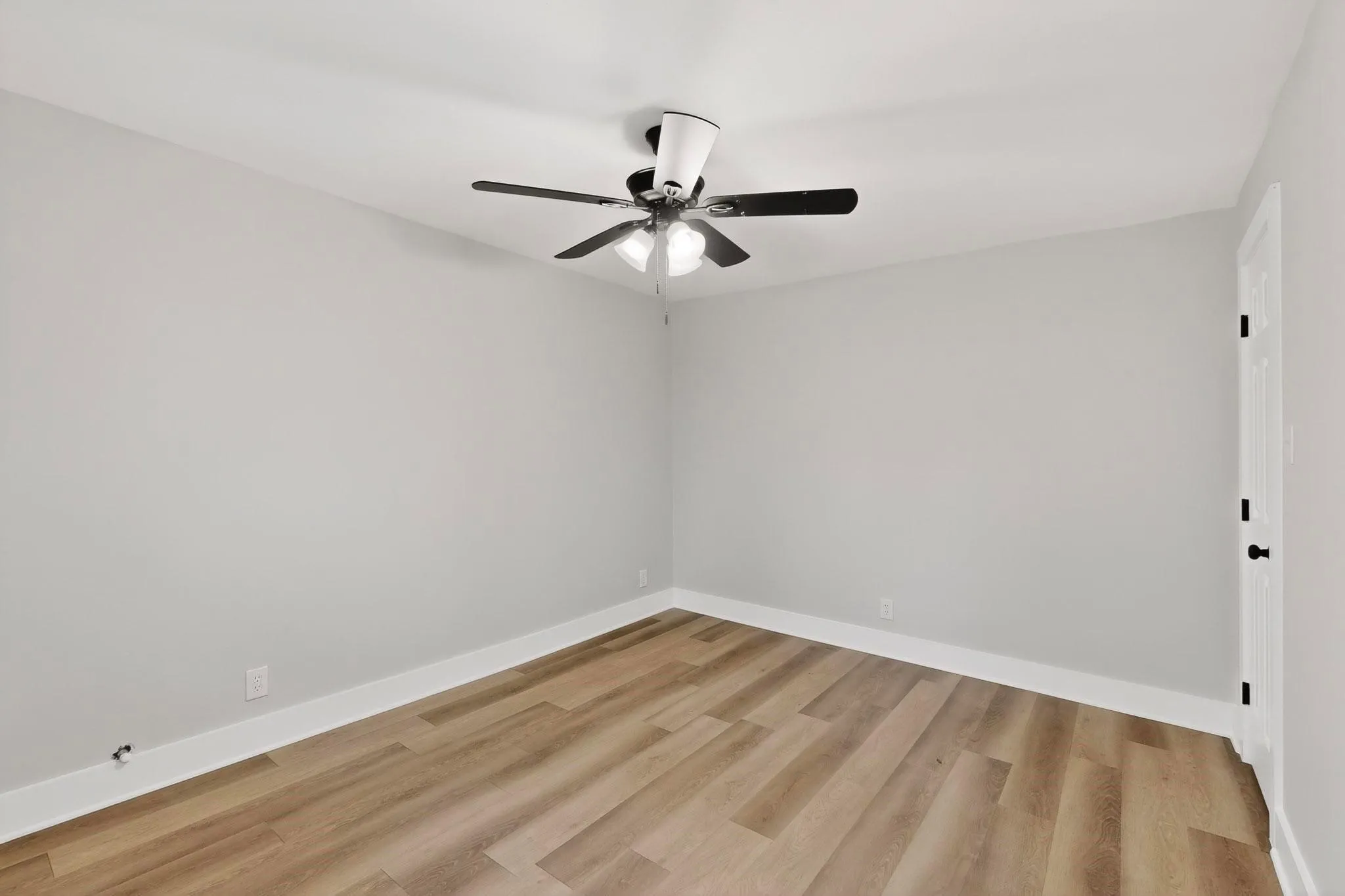 Open room featuring wood-finish flooring, white baseboards, and light gray walls