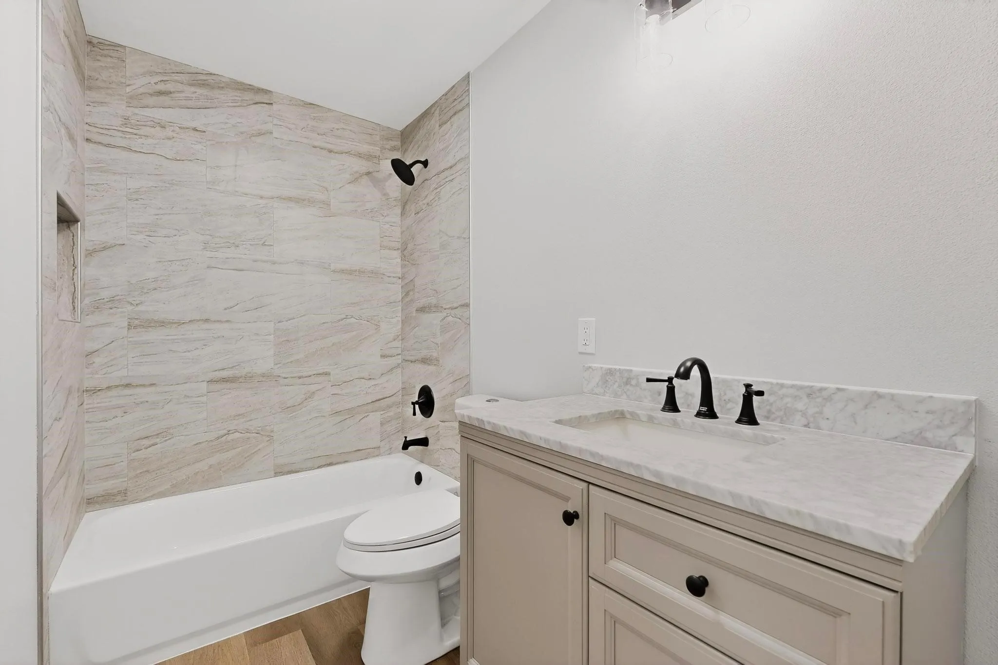 Bathroom featuring a bathtub with tiled surround, a built-in shower niche, and matte black fixtures