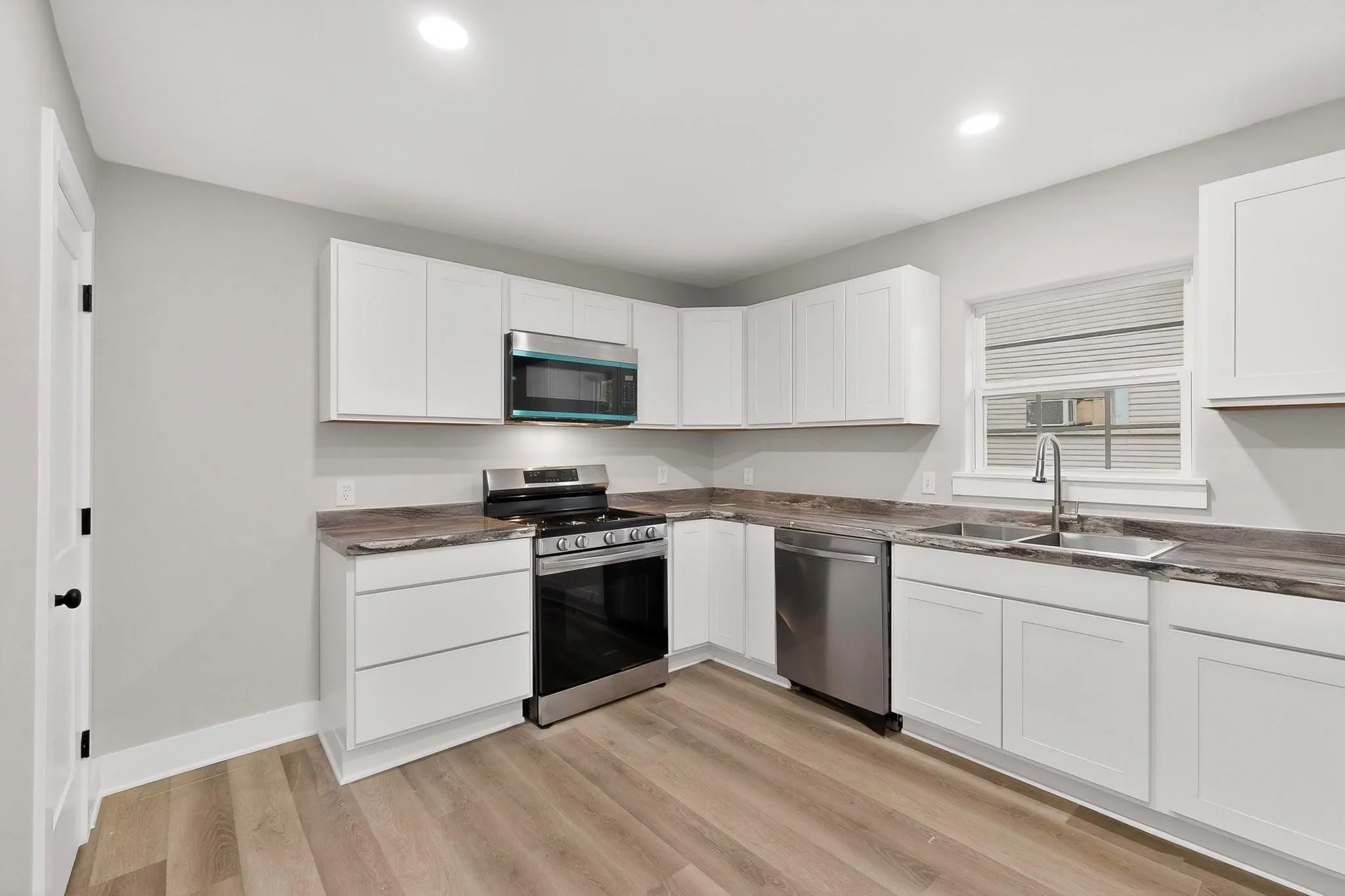 Kitchen featuring white cabinetry, wood-finish countertops, and stainless steel appliances including a range, microwave, and dishwasher