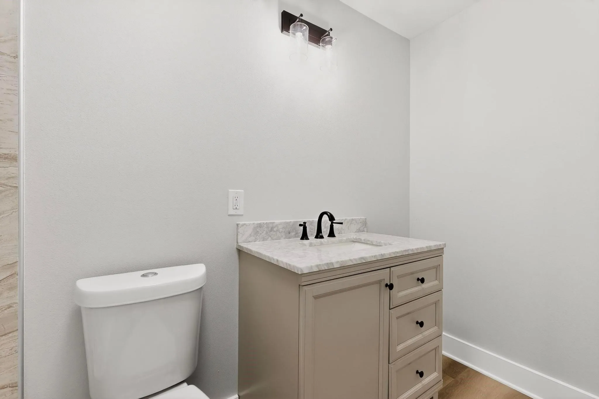 Bathroom featuring a single vanity with a light-toned cabinet, an integrated sink, and a stone-finish countertop