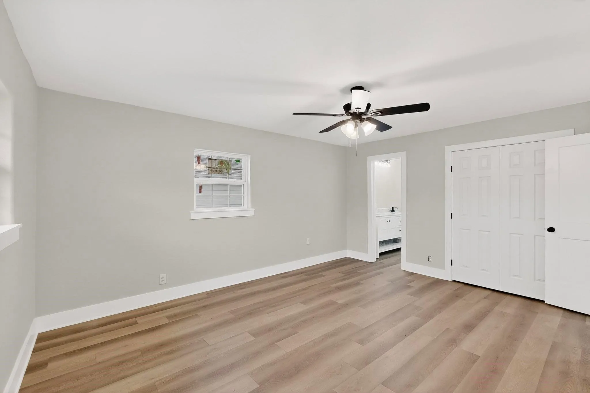 Spacious room featuring wood-finish flooring, light grey walls, and white trim