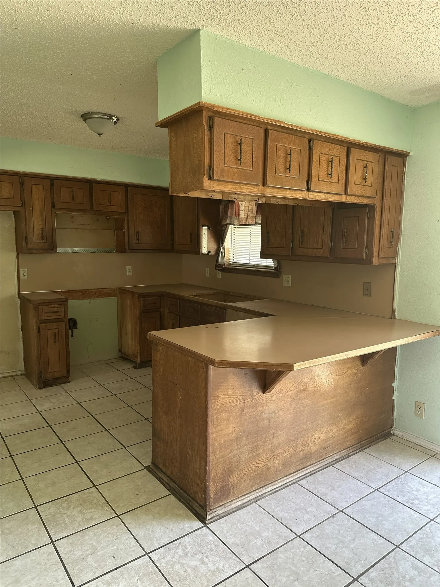 Kitchen featuring wood-finish cabinetry, tile flooring, and a built-in breakfast bar