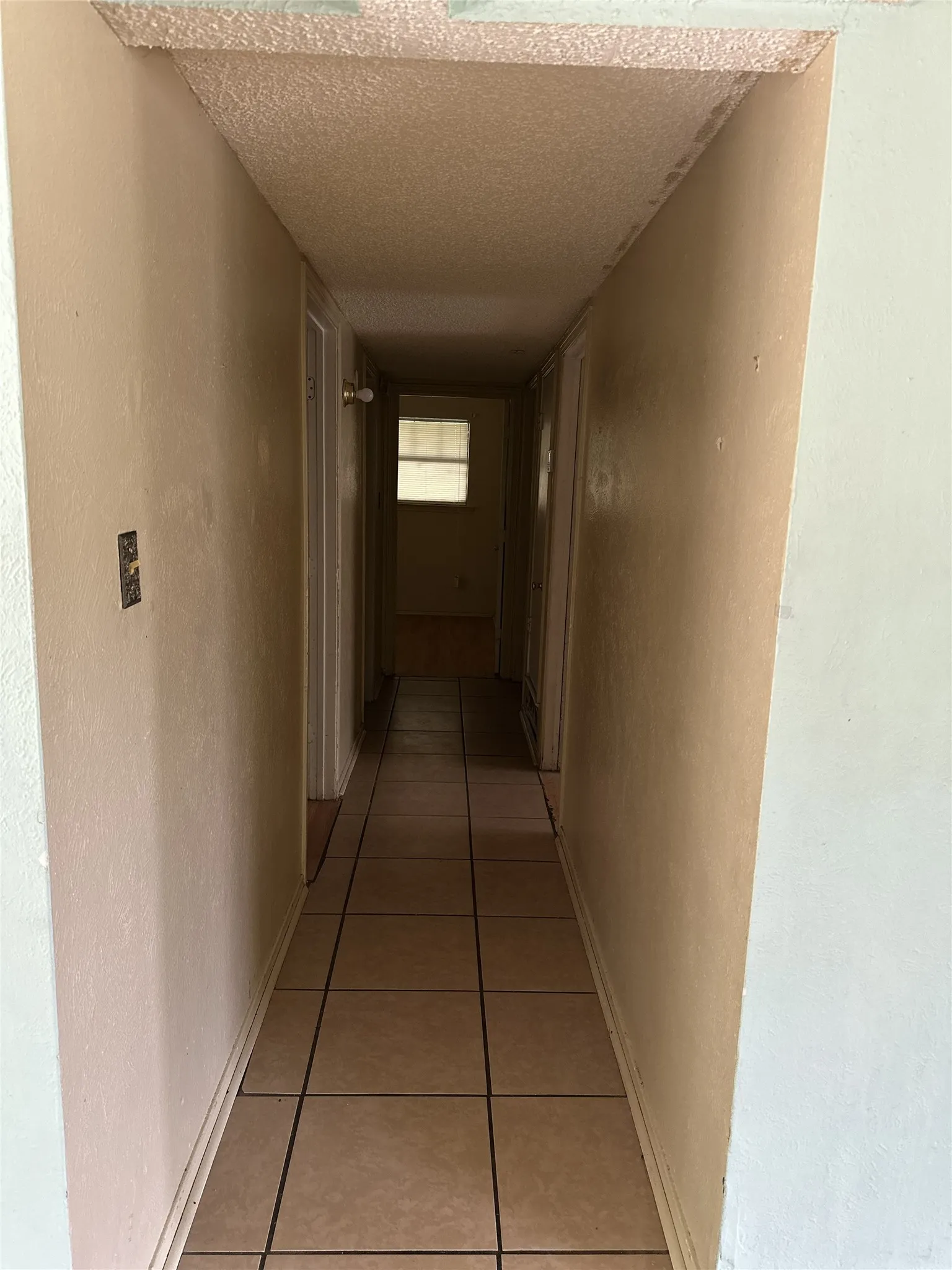 Hallway featuring light-toned tile flooring and painted walls