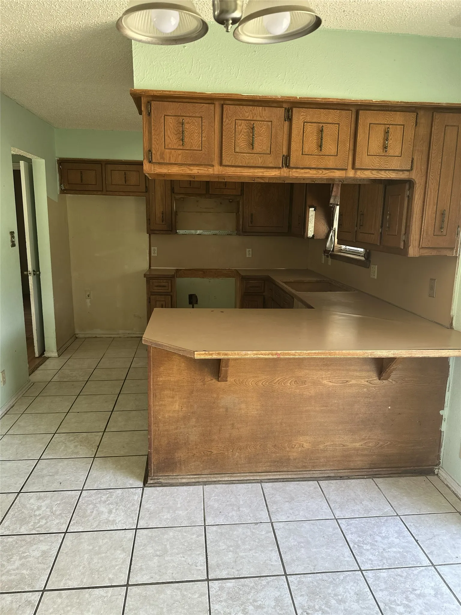 Kitchen featuring wood cabinetry, a breakfast bar, laminate countertops, and tile flooring
