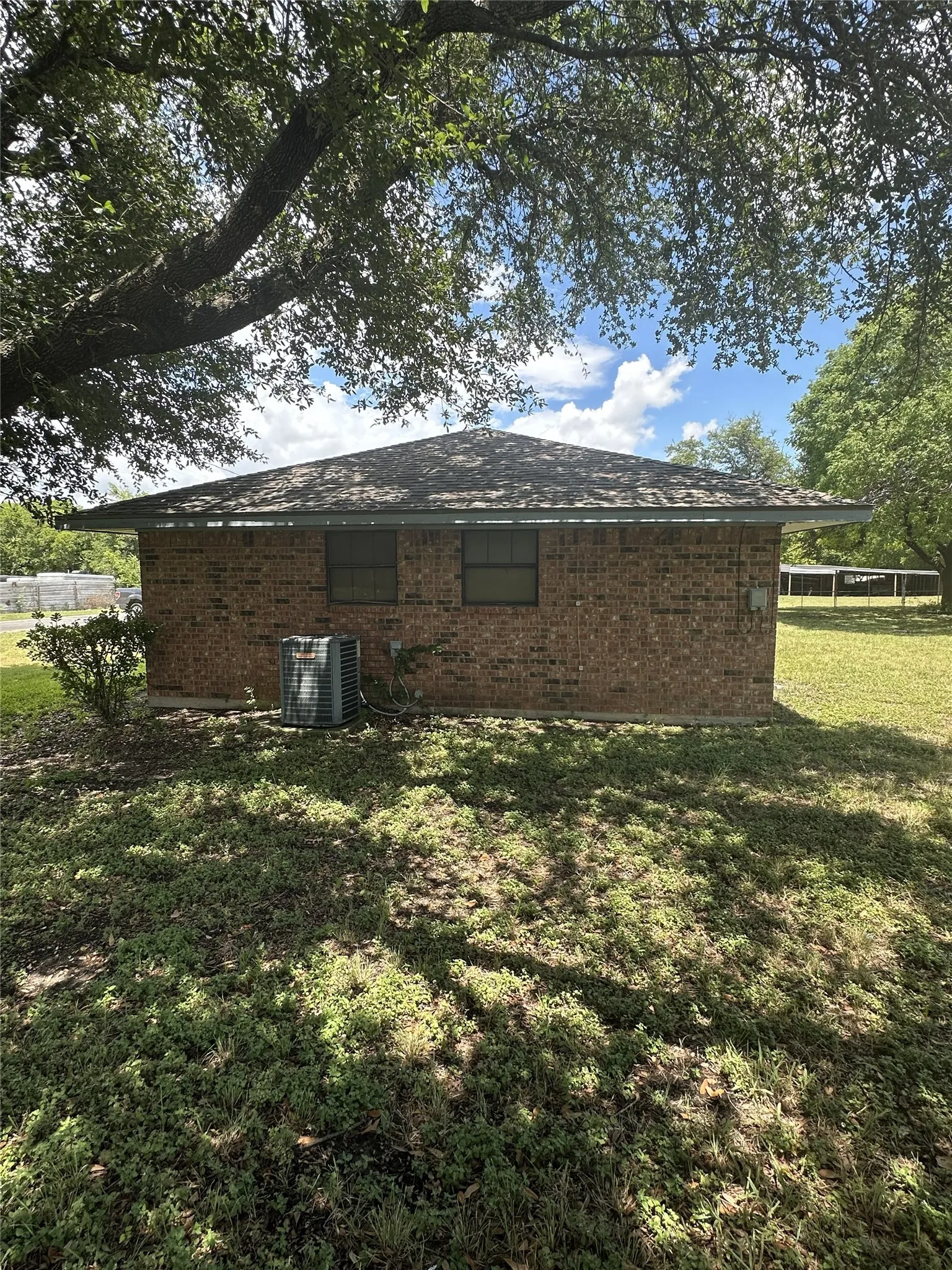 Brick exterior featuring a hip roof, two windows, and an outdoor HVAC unit