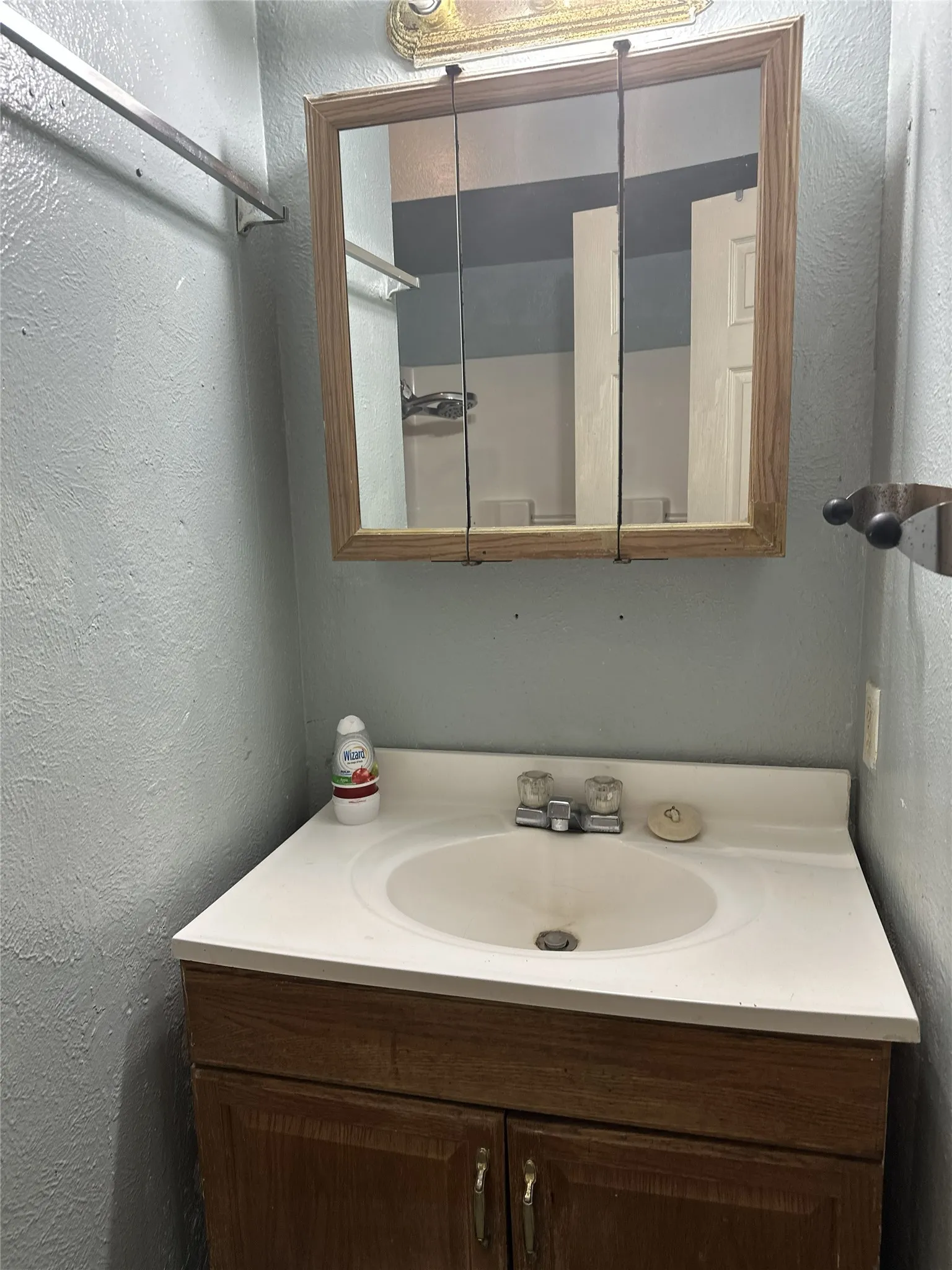 Bathroom vanity with a white countertop and integrated sink, set against a light blue wall