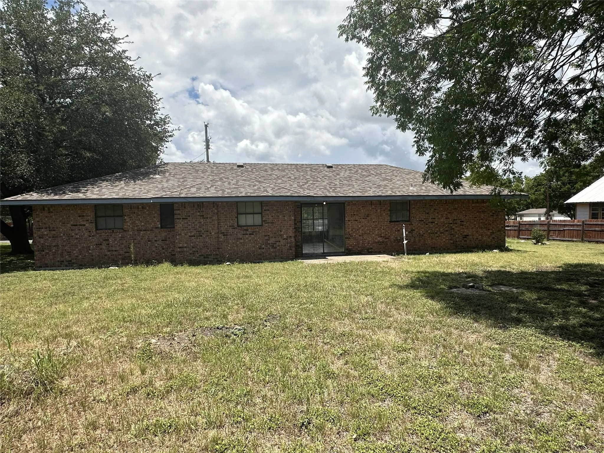 Brick exterior with a shingle roof and multiple windows
