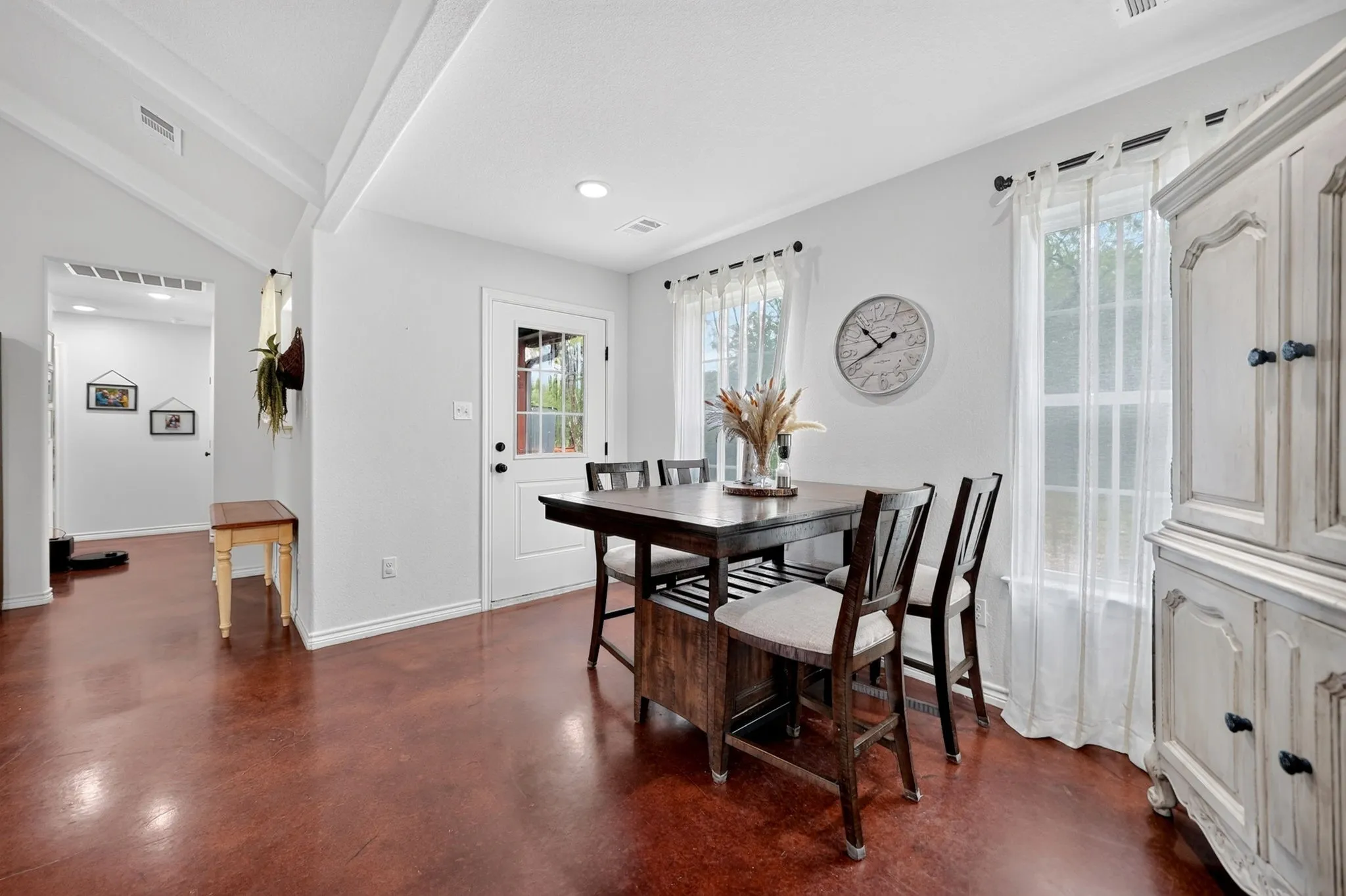 Bright dining area featuring rich-toned flooring, an exterior door with glass panels, recessed lighting, and multiple windows