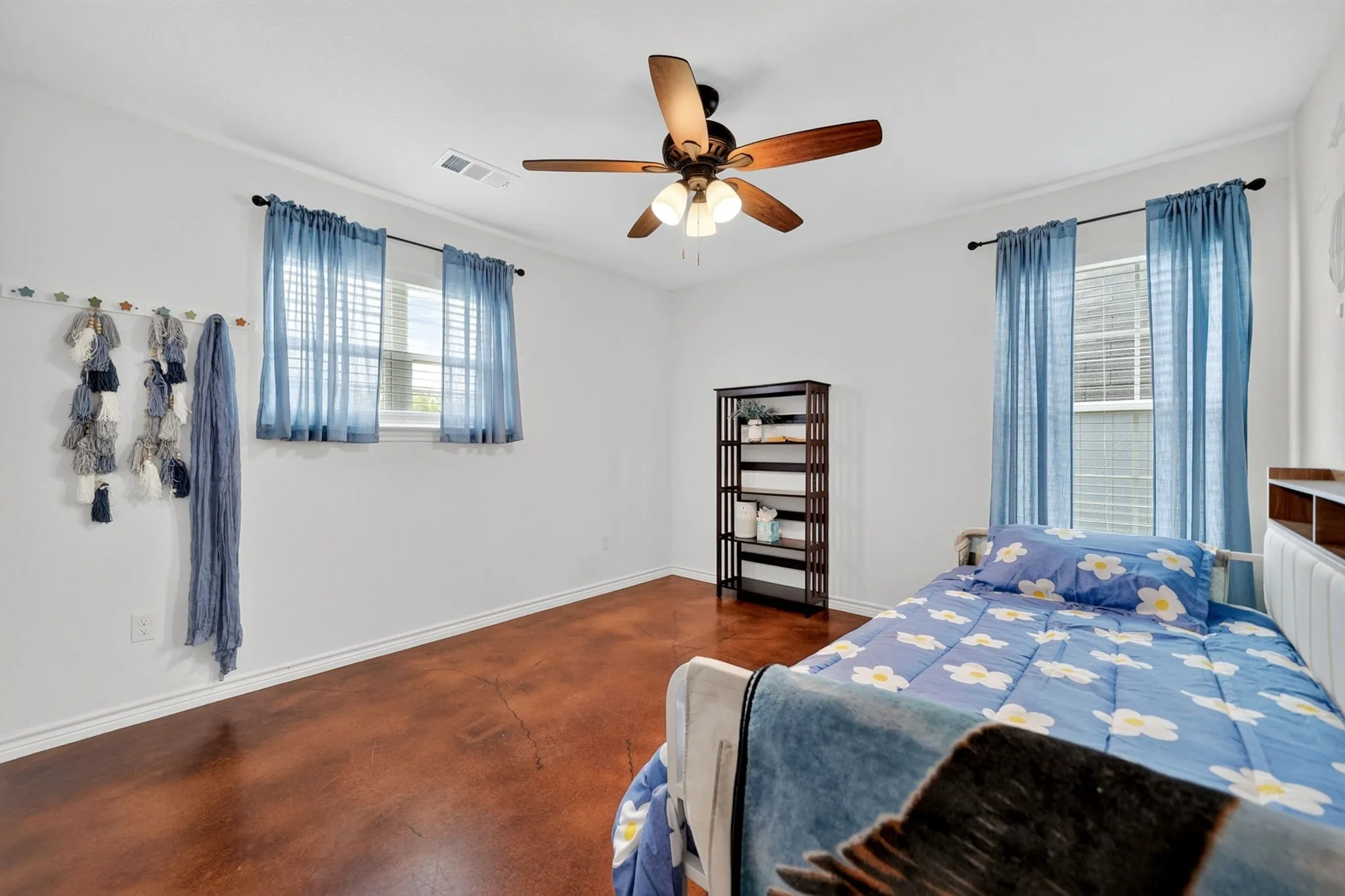 Bright room featuring durable flooring, two windows with window treatments, a ceiling fan, and white walls