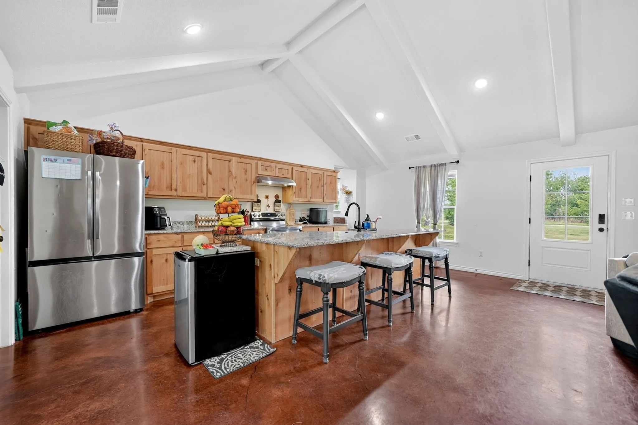 Kitchen featuring wood cabinetry, stainless steel appliances, and an island with a stone countertop