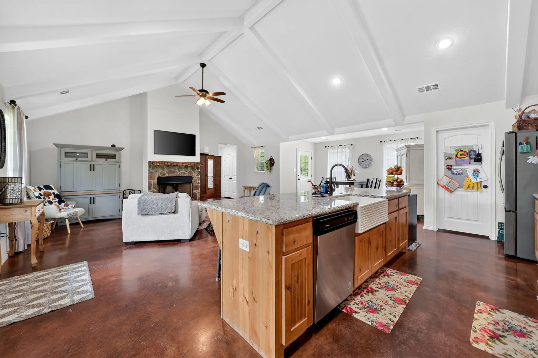 Open-concept living space with vaulted ceilings featuring exposed white beams