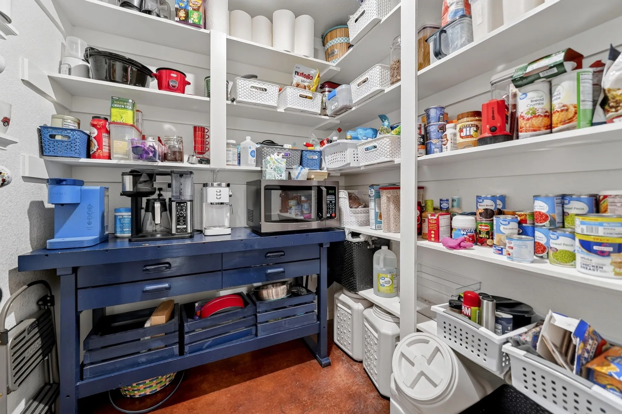 Expansive pantry featuring extensive built-in shelving, a dedicated counter space, and durable flooring