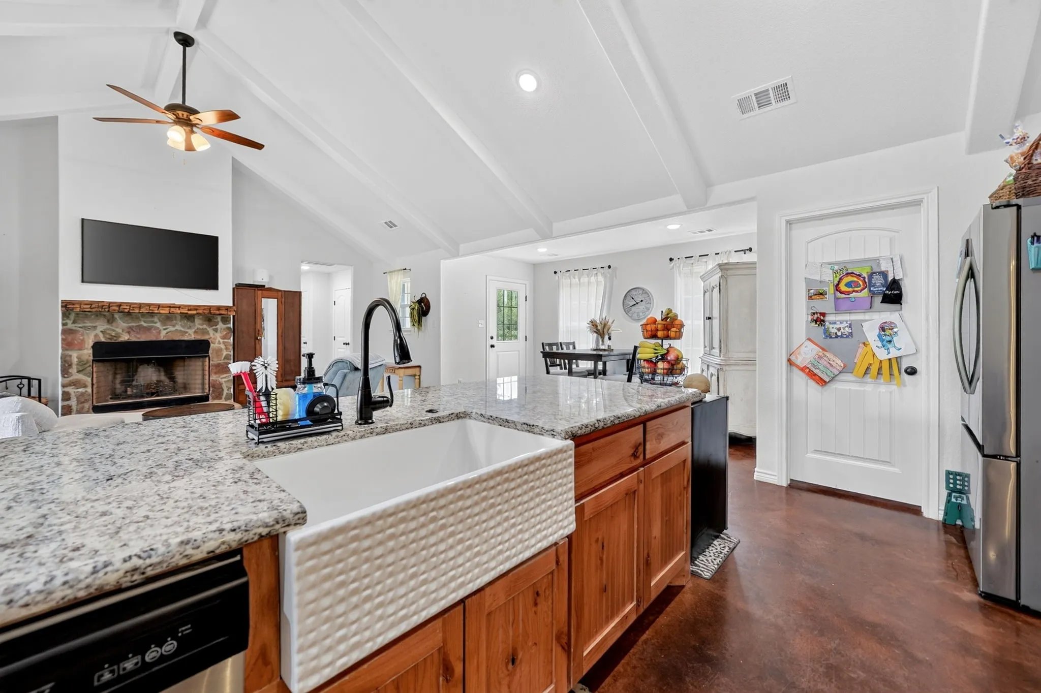 Kitchen island with a white farmhouse sink, granite countertops, and wood cabinetry