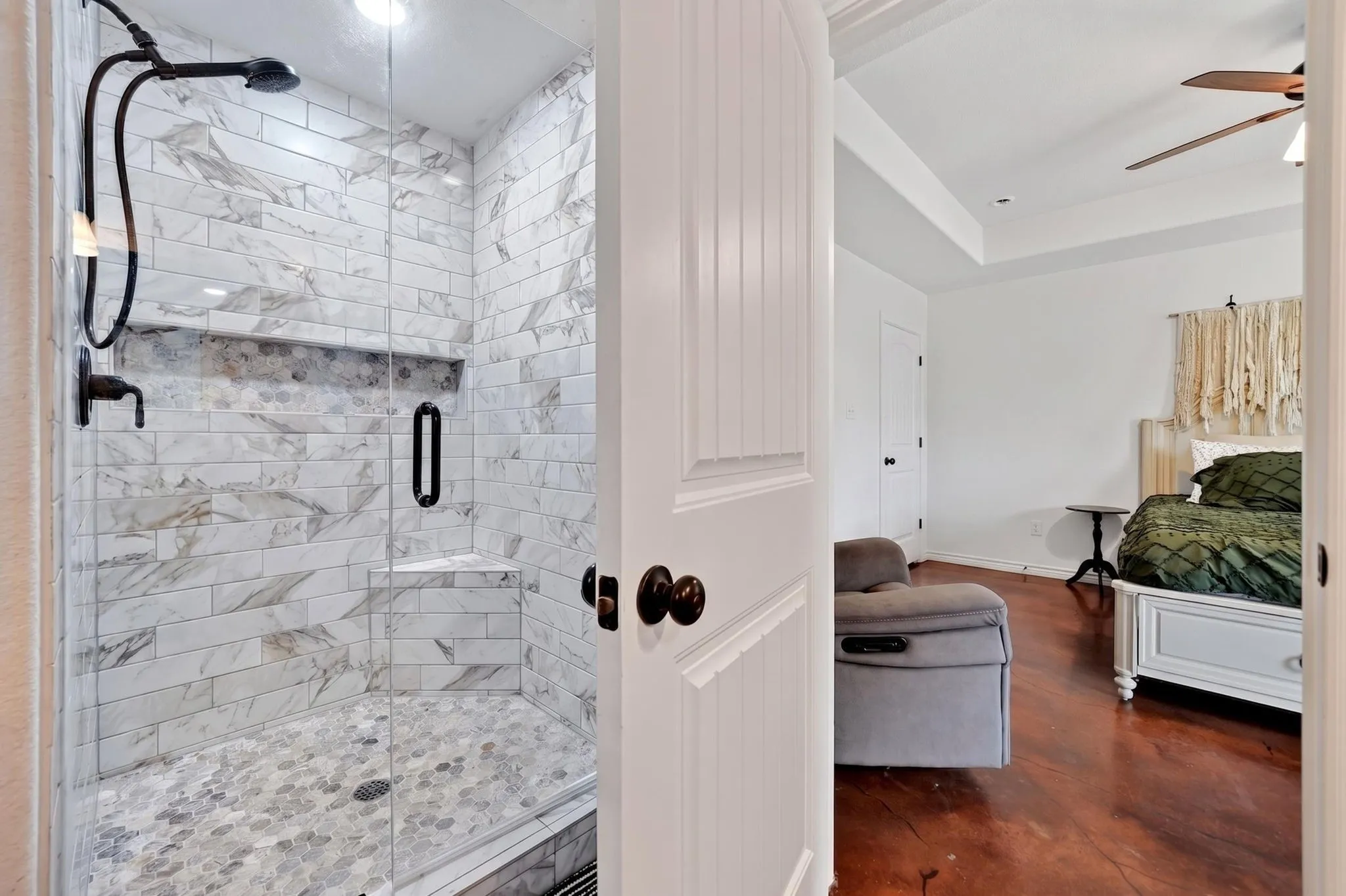 Walk-in shower featuring subway tile with gray veining, a built-in niche, and a corner bench