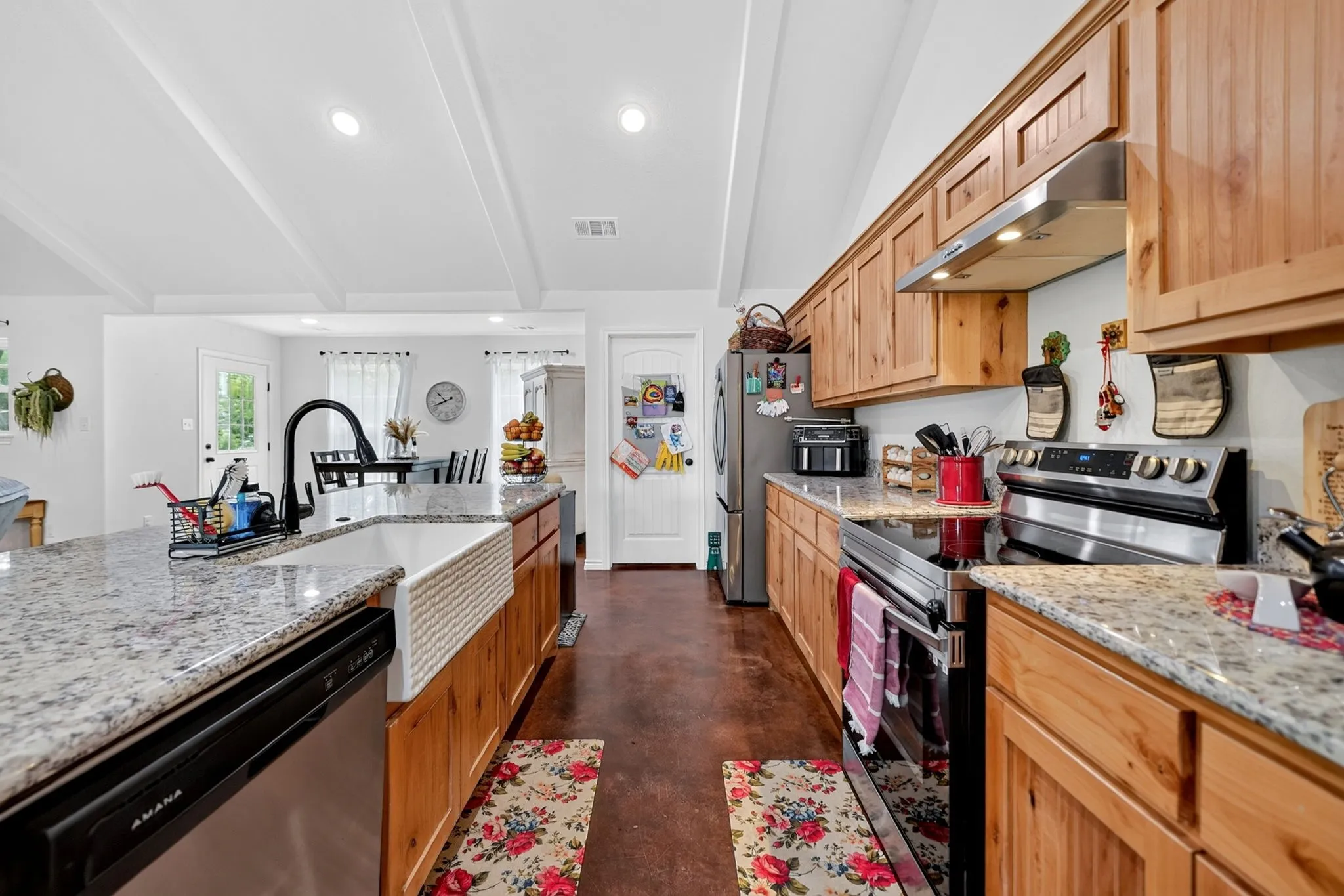 Kitchen featuring granite countertops, wood-finish cabinetry, stainless steel appliances, a farmhouse sink with a gooseneck faucet, and recessed lighting