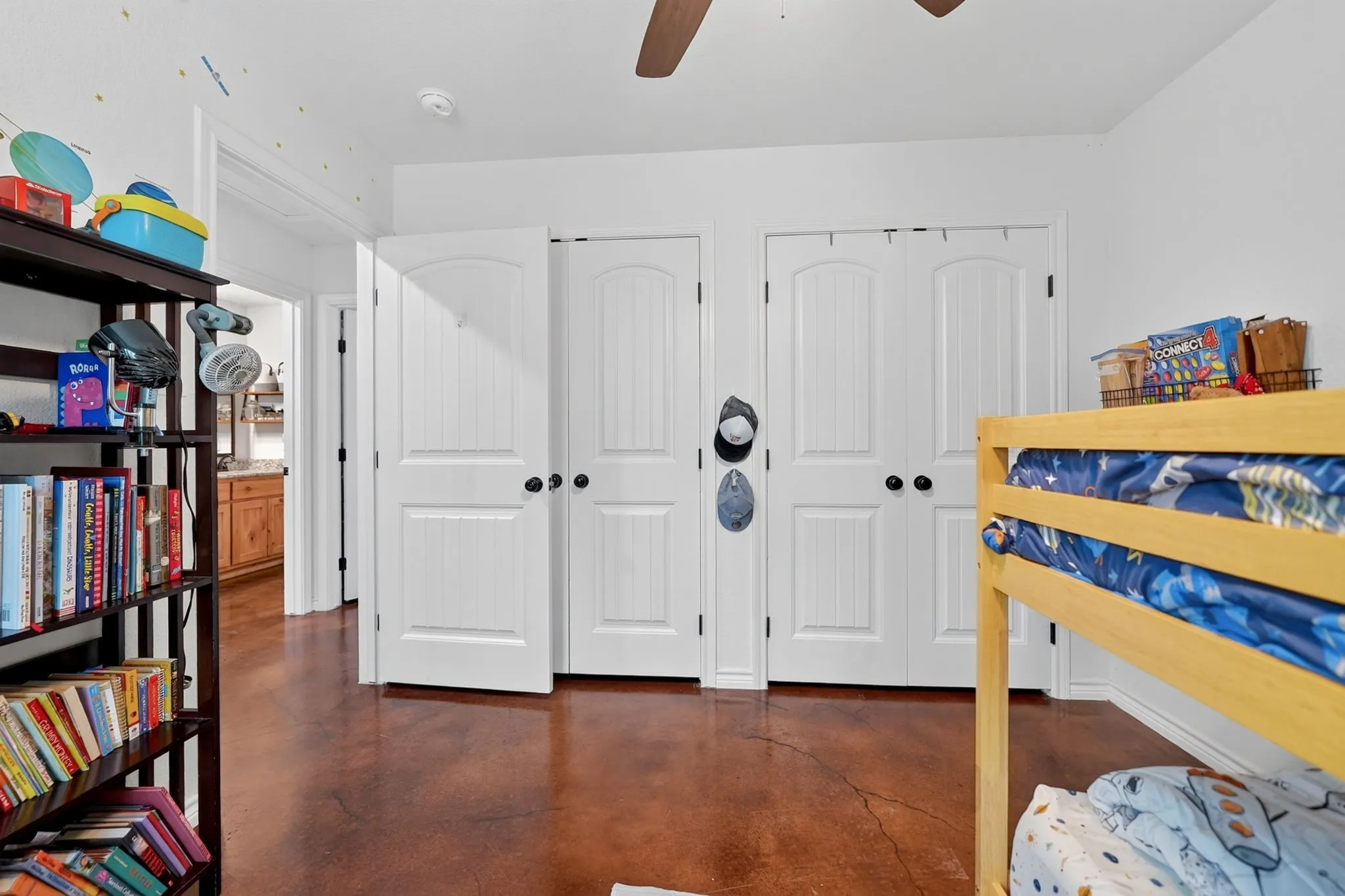White interior doors with black hardware, brown-toned flooring, and a ceiling fan