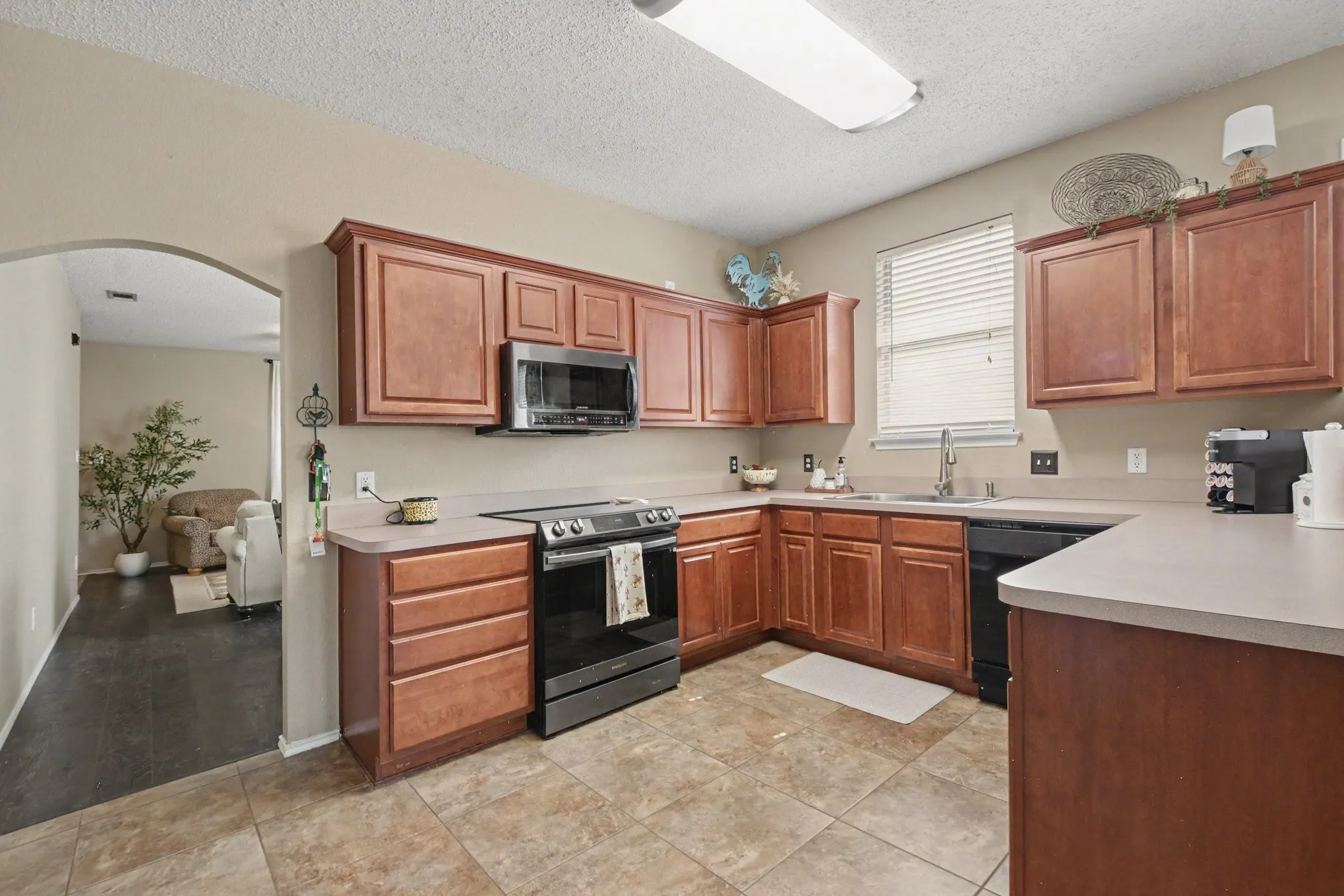 Kitchen featuring wood-finish cabinetry, a stainless steel over-the-range microwave, and a black electric range