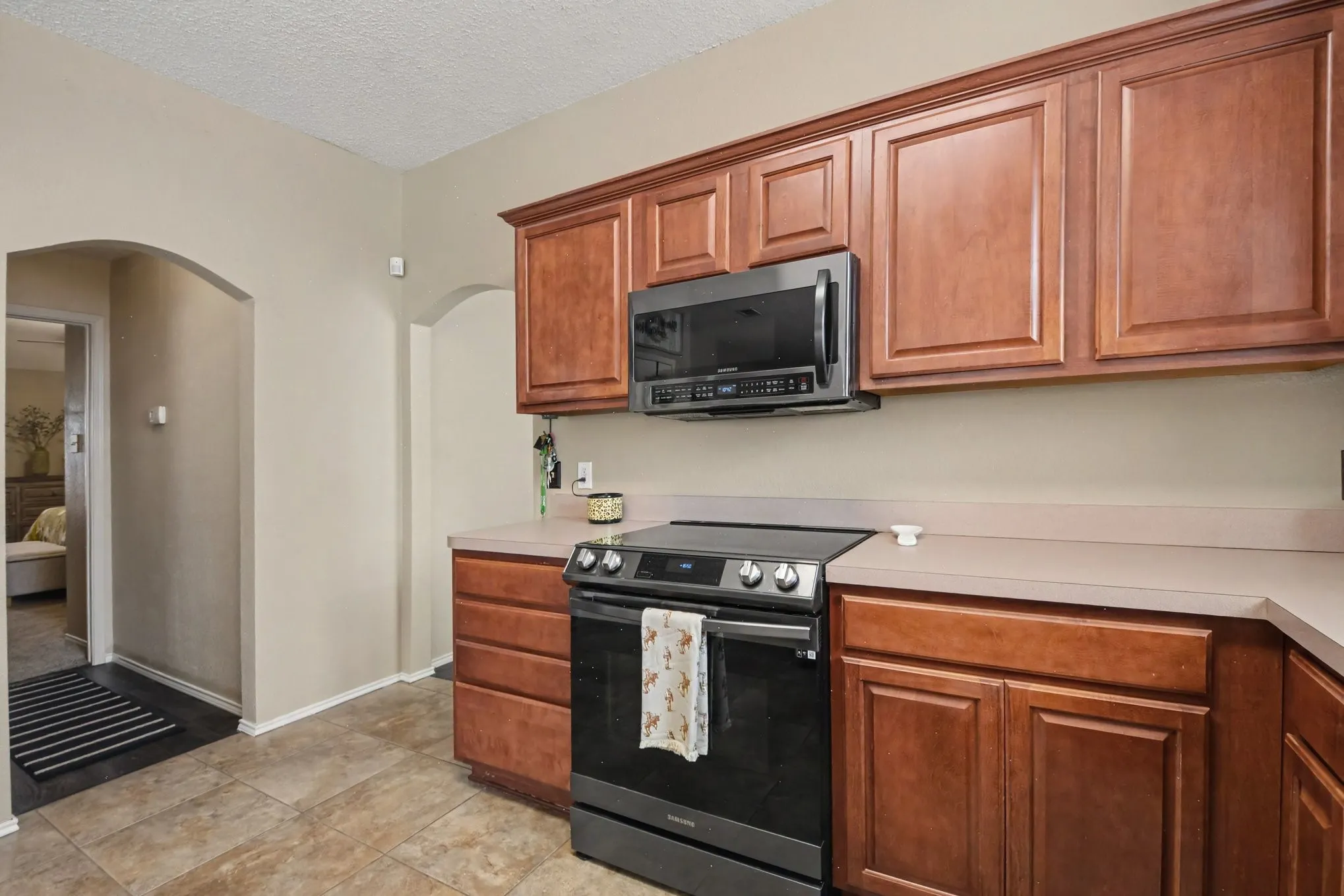 Kitchen featuring wood cabinetry, stone-finish countertops, and tile flooring