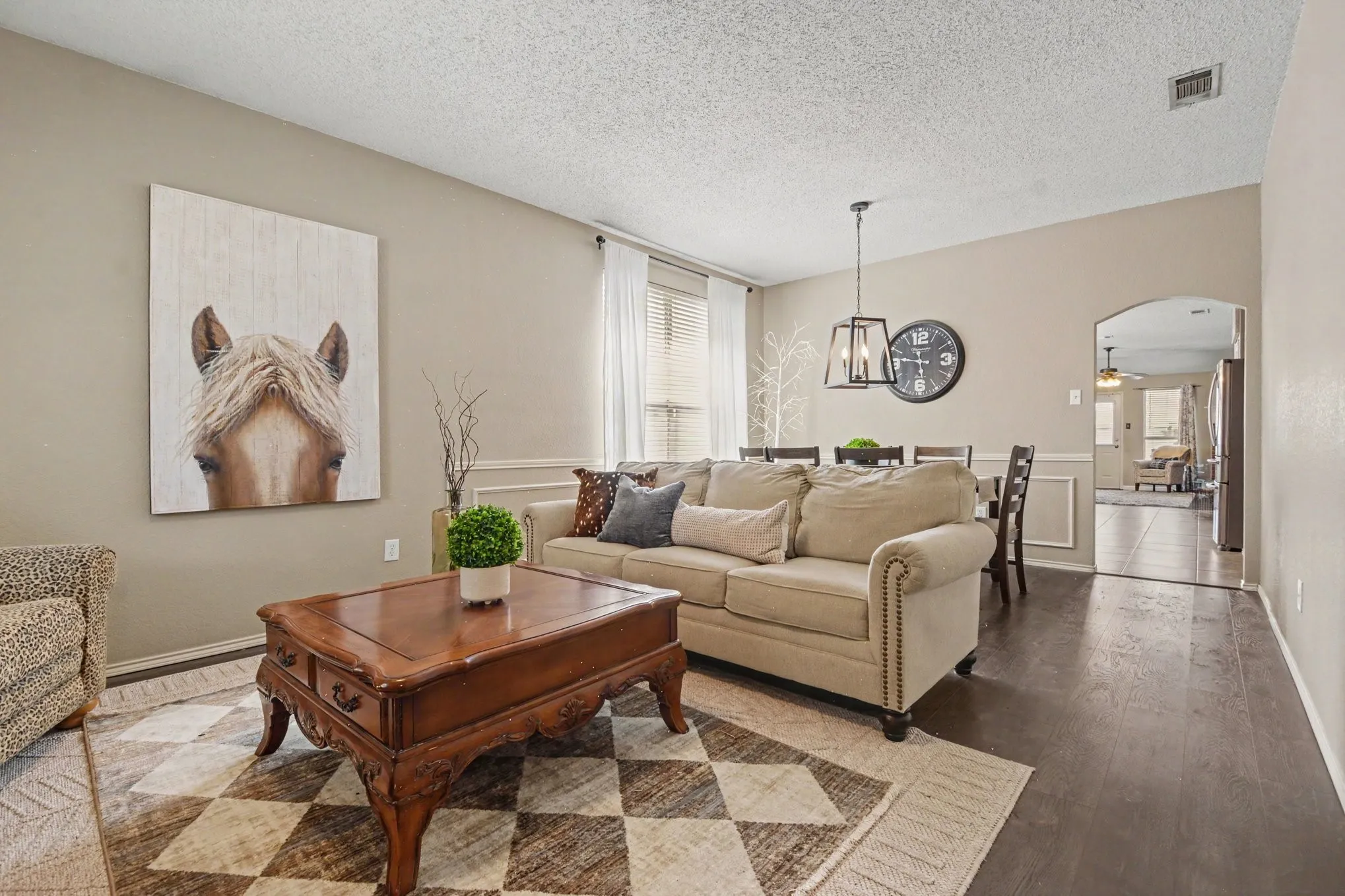 Open-concept living space featuring wood-finish flooring, neutral wall tones, and arched doorways