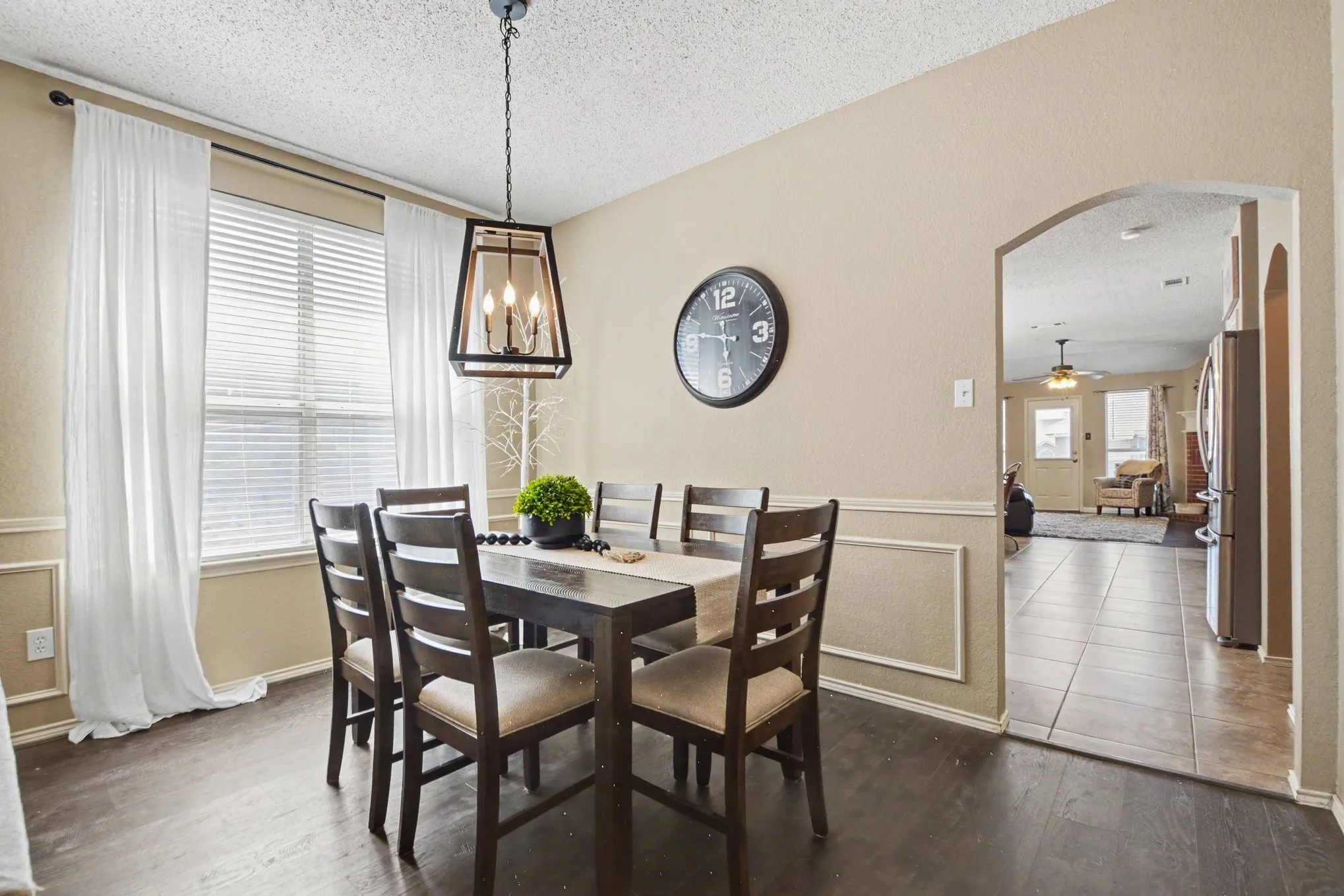 Dining area featuring wood-finish flooring, a contemporary black metal chandelier, and a large window with blinds