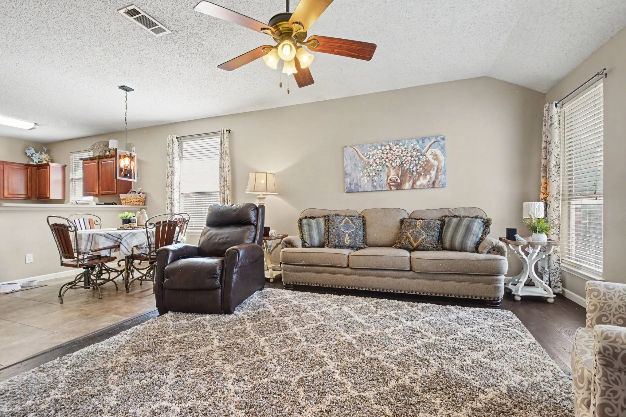 Spacious living area featuring a vaulted ceiling and a ceiling fan with integrated lighting